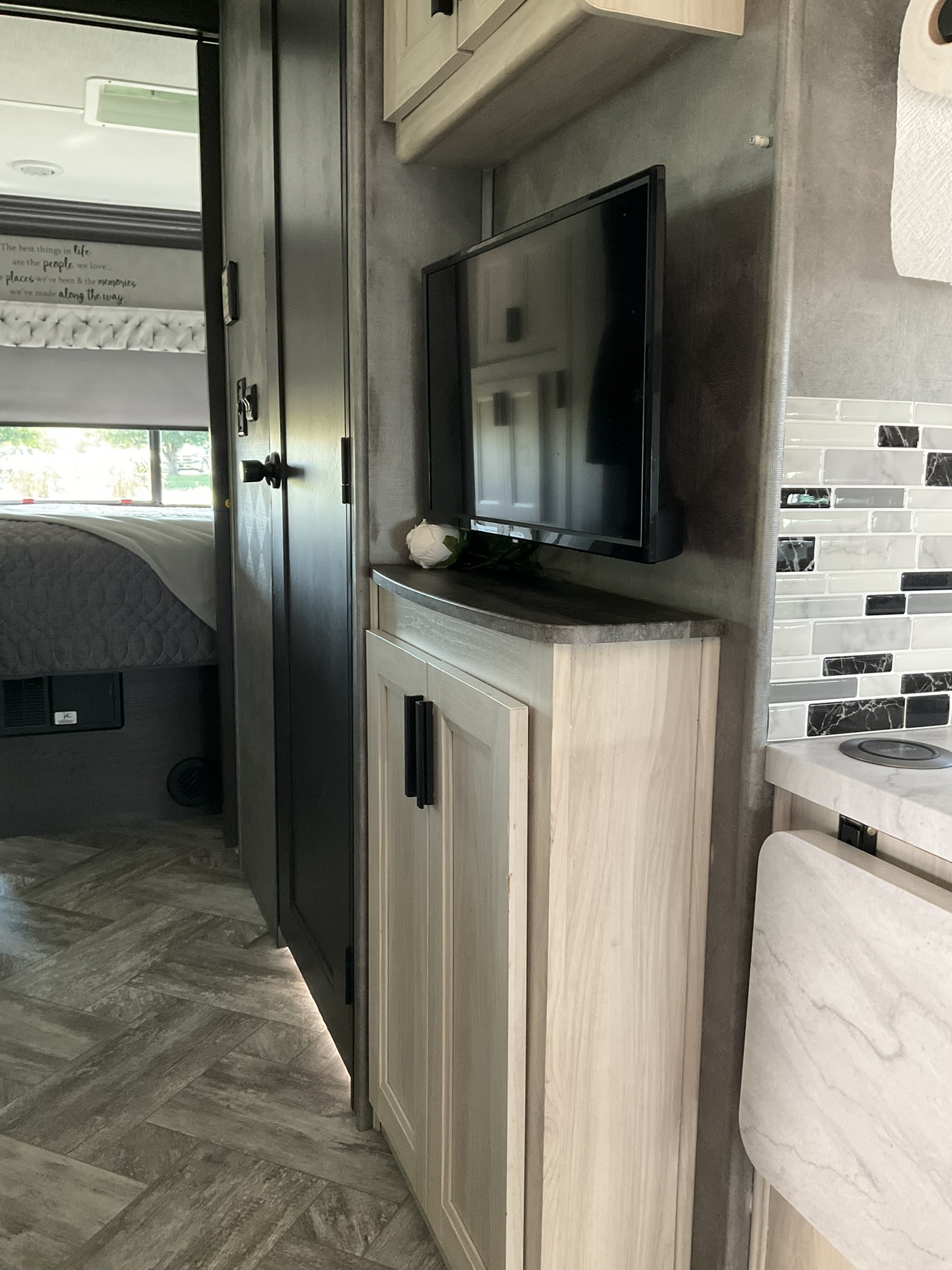 Stylish RV rental interior: view from living area into bedroom, featuring kitchen backsplash, TV, and light wood cabinetry.. Forest River Sunseeker LE 2022