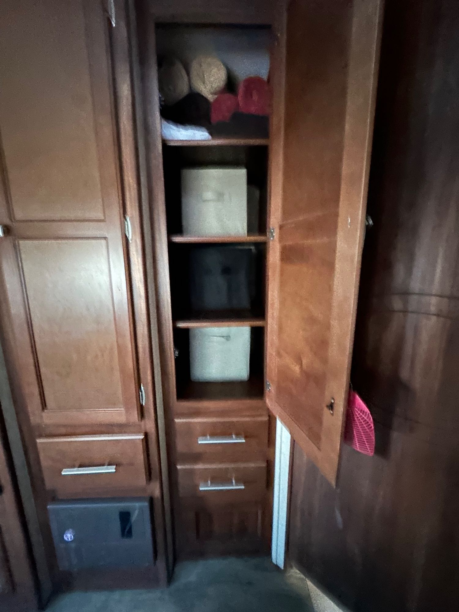 RV rental interior: A wooden cabinet with an open door reveals organized shelves holding bins and various items.. Heartland RVs Wilderness 2016