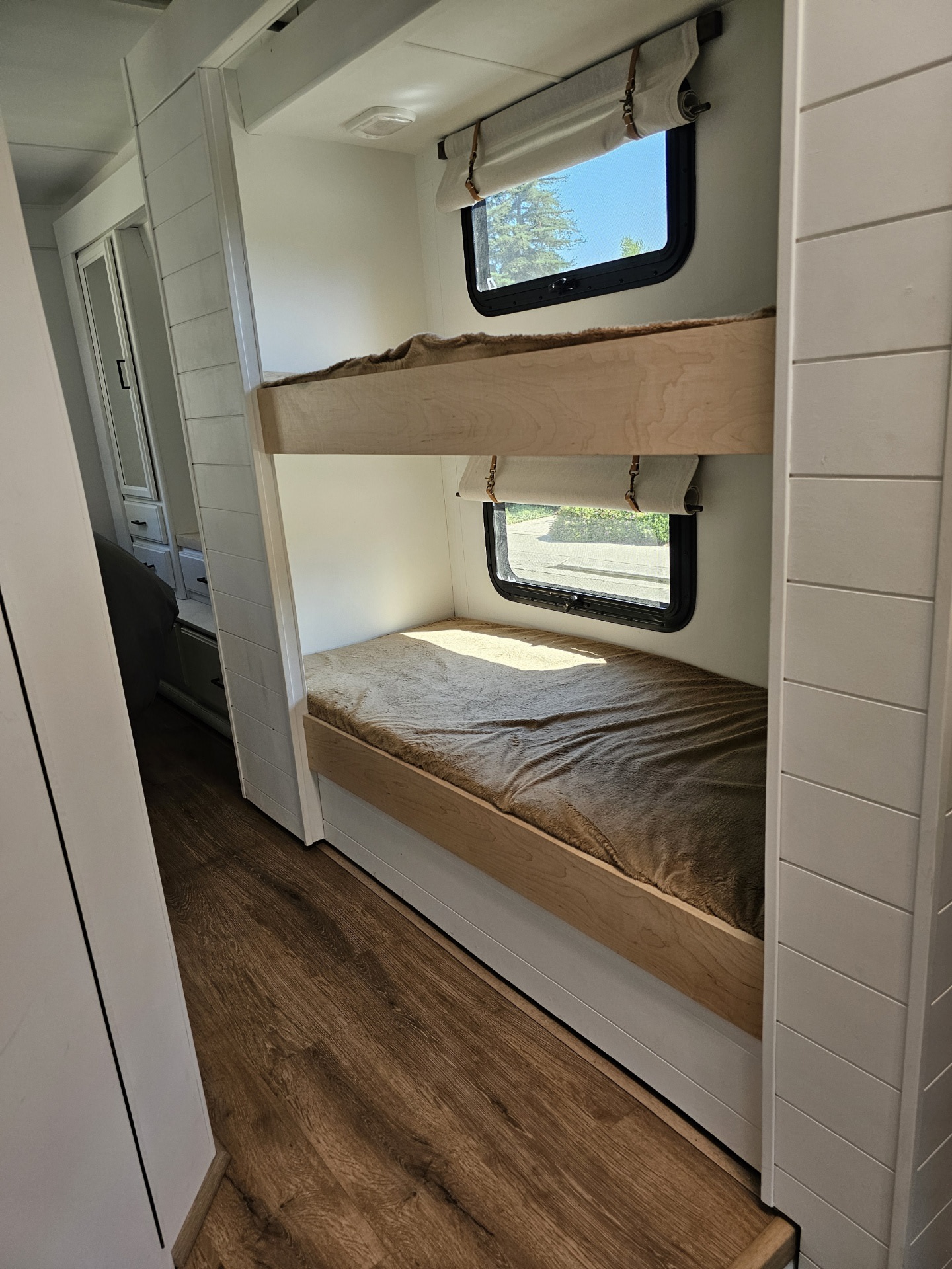 Modern RV rental interior featuring comfortable bunk beds with windows and cozy blankets, ideal for family travel.. Thor Four Winds 2015