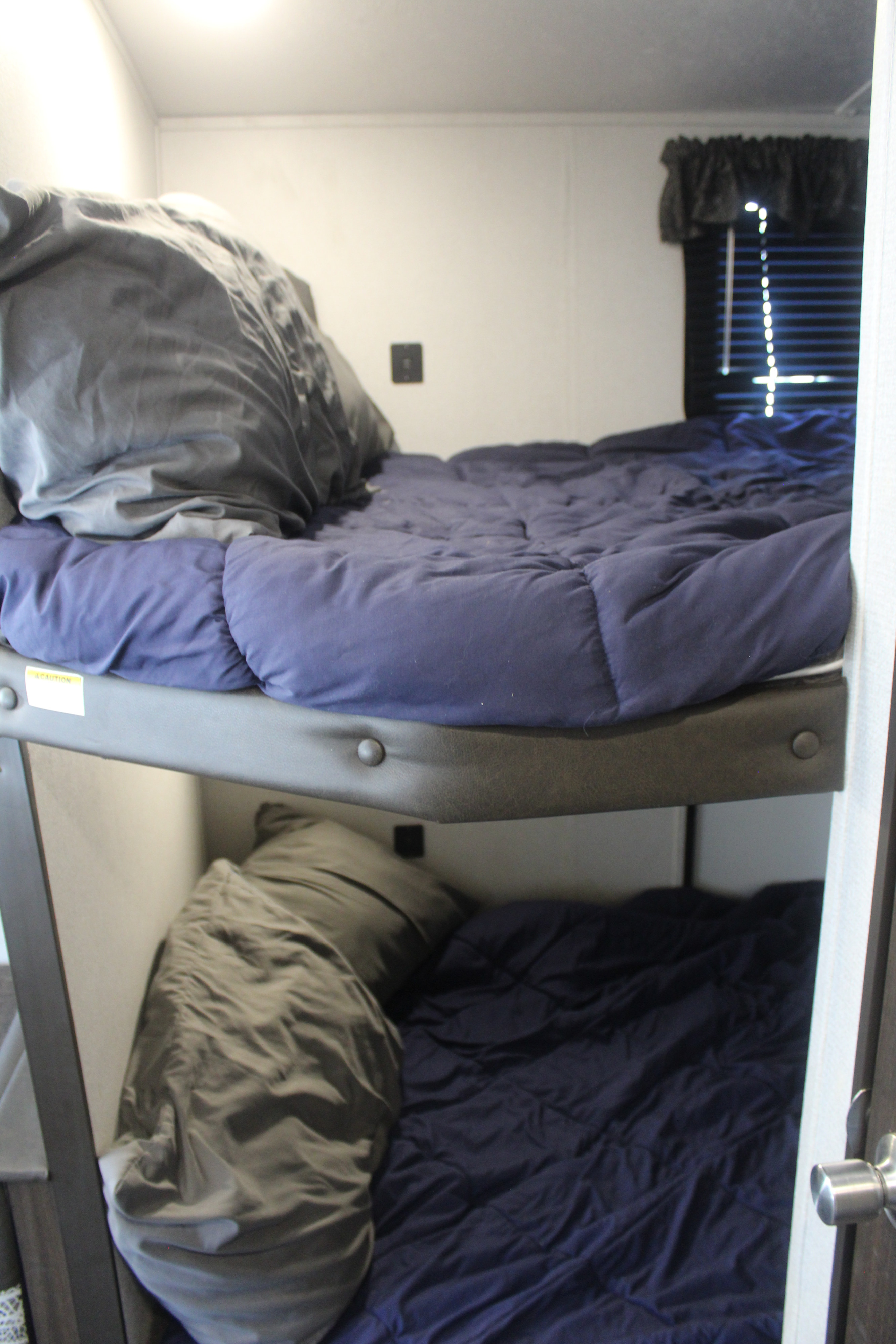 Cozy RV rental bunk beds, two levels with dark blue comforters and pillows. Ideal for family adventures.. Keystone RV Springdale 2020
