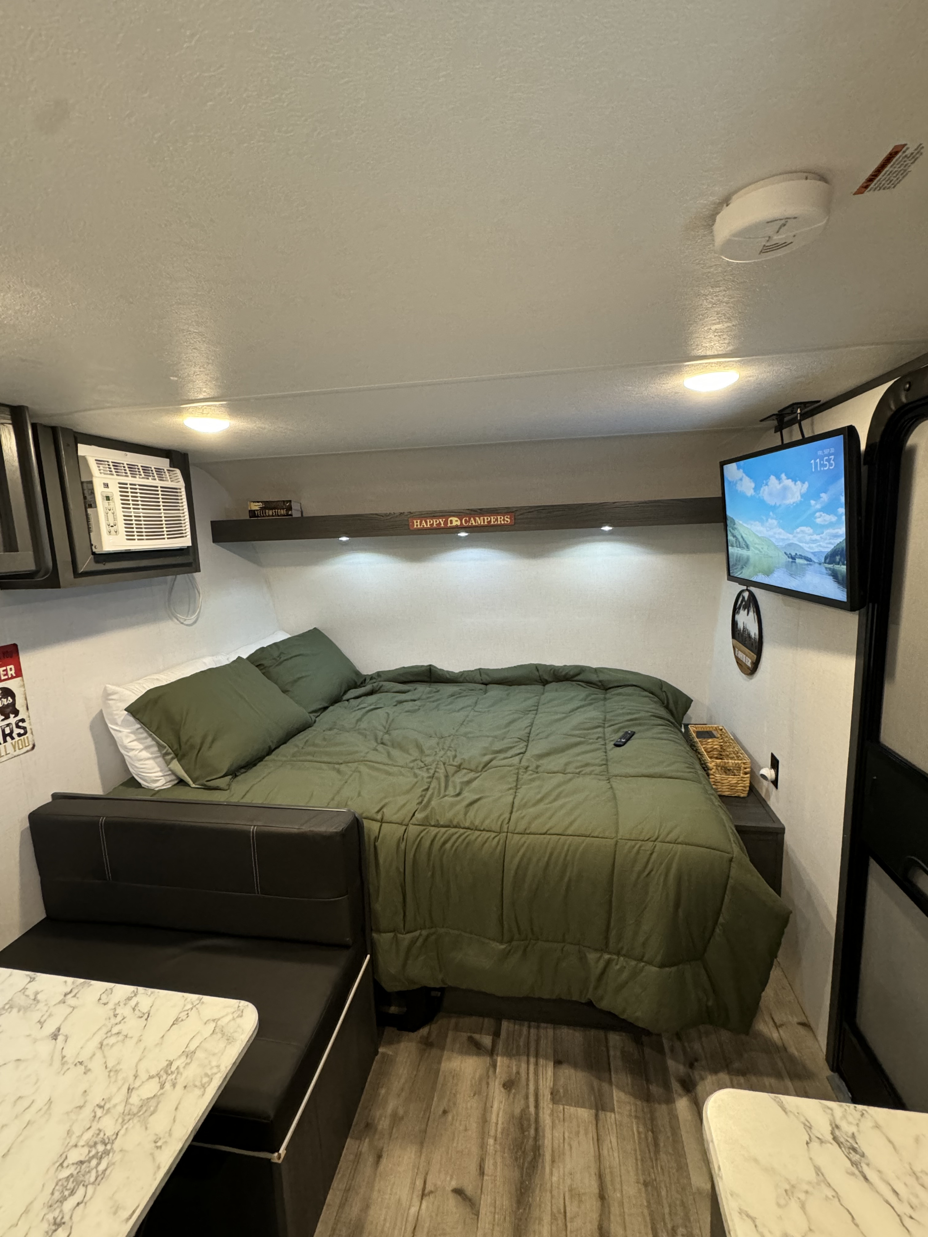 RV rental interior features a green bed, mounted TV, AC, and dining booth with marble table.. 4YDTATG12S8920000 Dutchmen Aspen Trail 17BH (0000) 2025