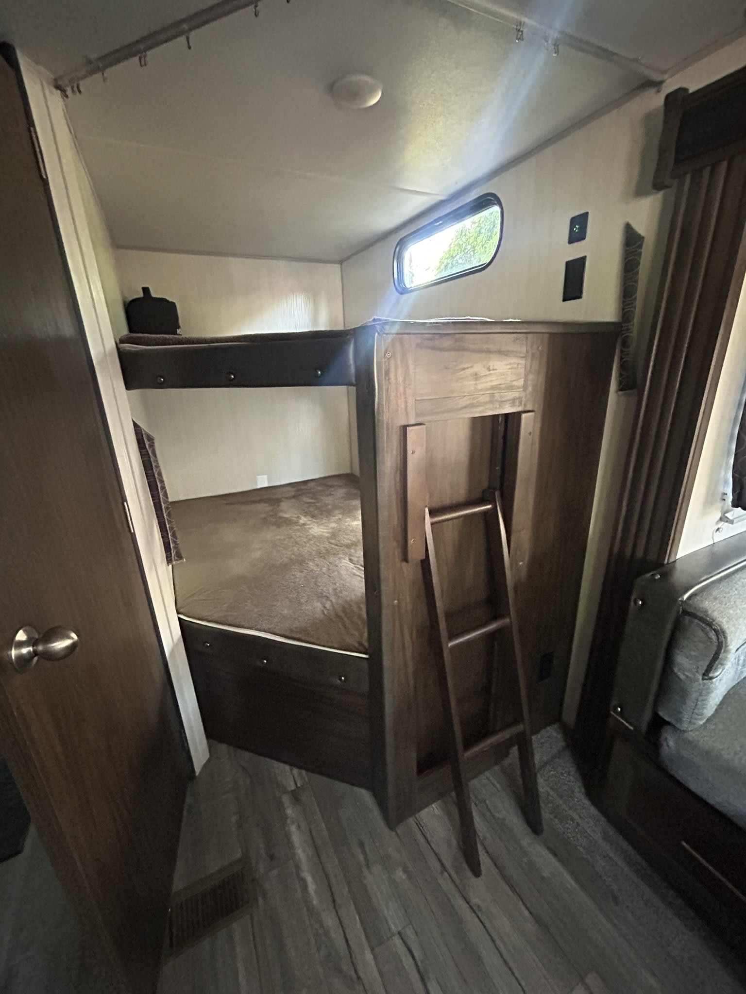 Comfortable bunk beds with a ladder in an RV rental, featuring wood-look flooring and a small window.. Forest River Cherokee Grey Wolf 2019