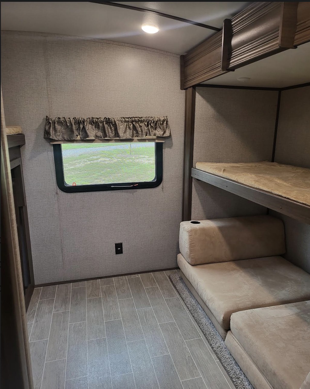 RV rental bunk room with upper and lower beds, a large window, and modular lounge seating for travelers.. Keystone Laredo 2020