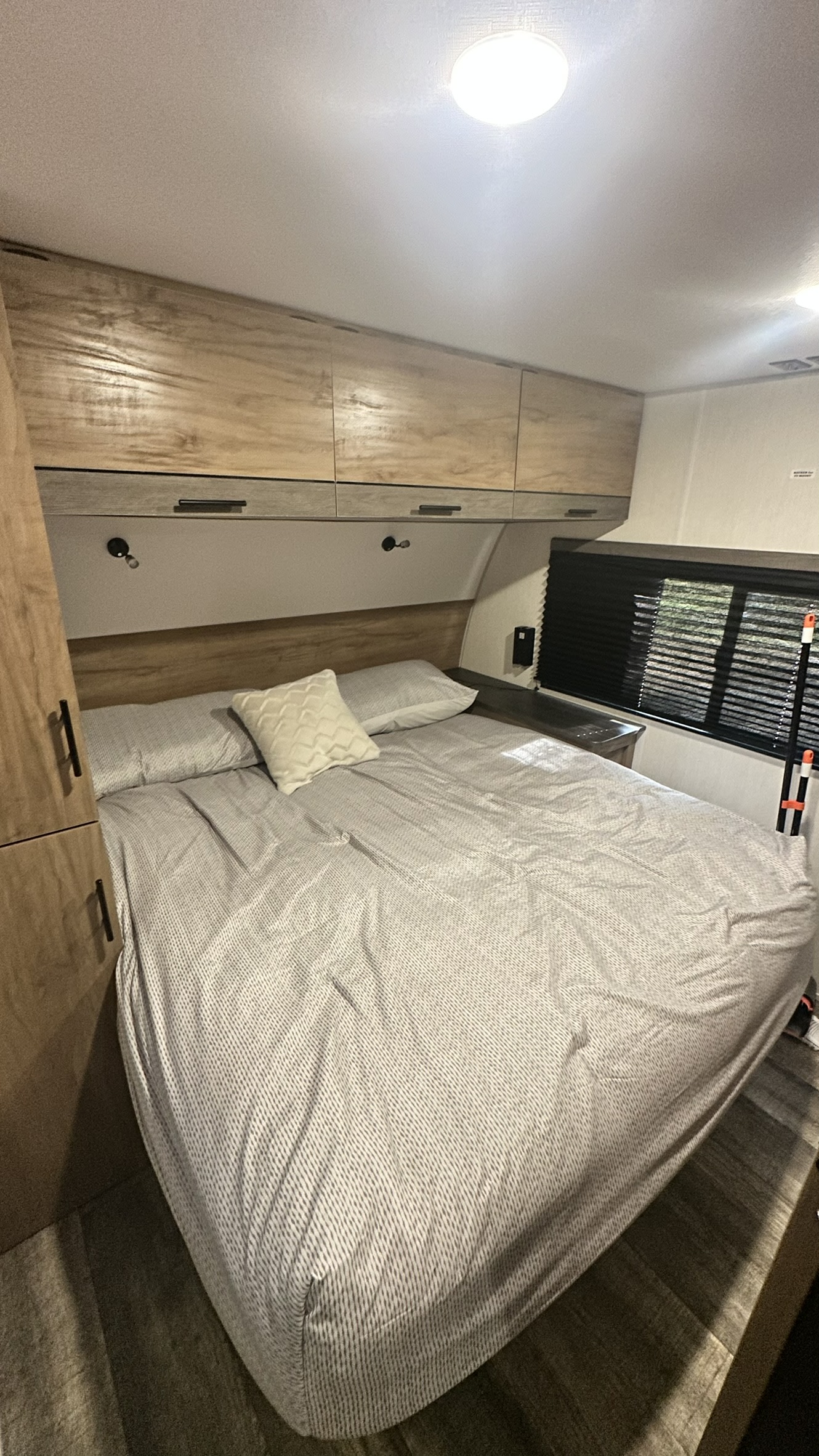 Inside an RV rental: a compact bedroom with a cozy bed, overhead cabinets, and a window. Ideal for travel.. Forest River Campsite Reserve 2025
