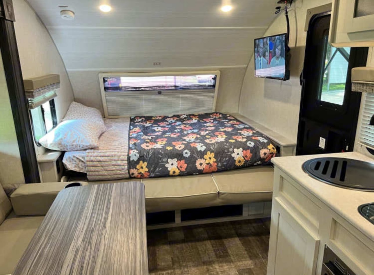 Cozy RV rental interior featuring a bed, dining area, TV, and kitchenette. Perfect for travel.. R-Pod R-Pod Trailer 2022