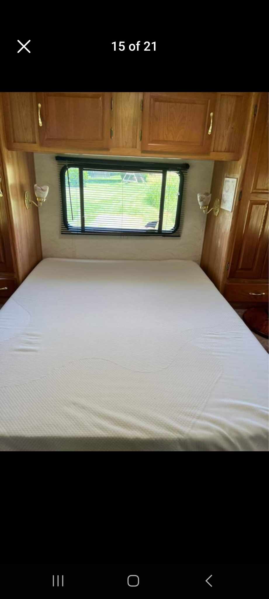 Spacious RV rental bedroom with comfortable bed, window, and wood cabinetry for a cozy stay.. Coachmen Santara 1998