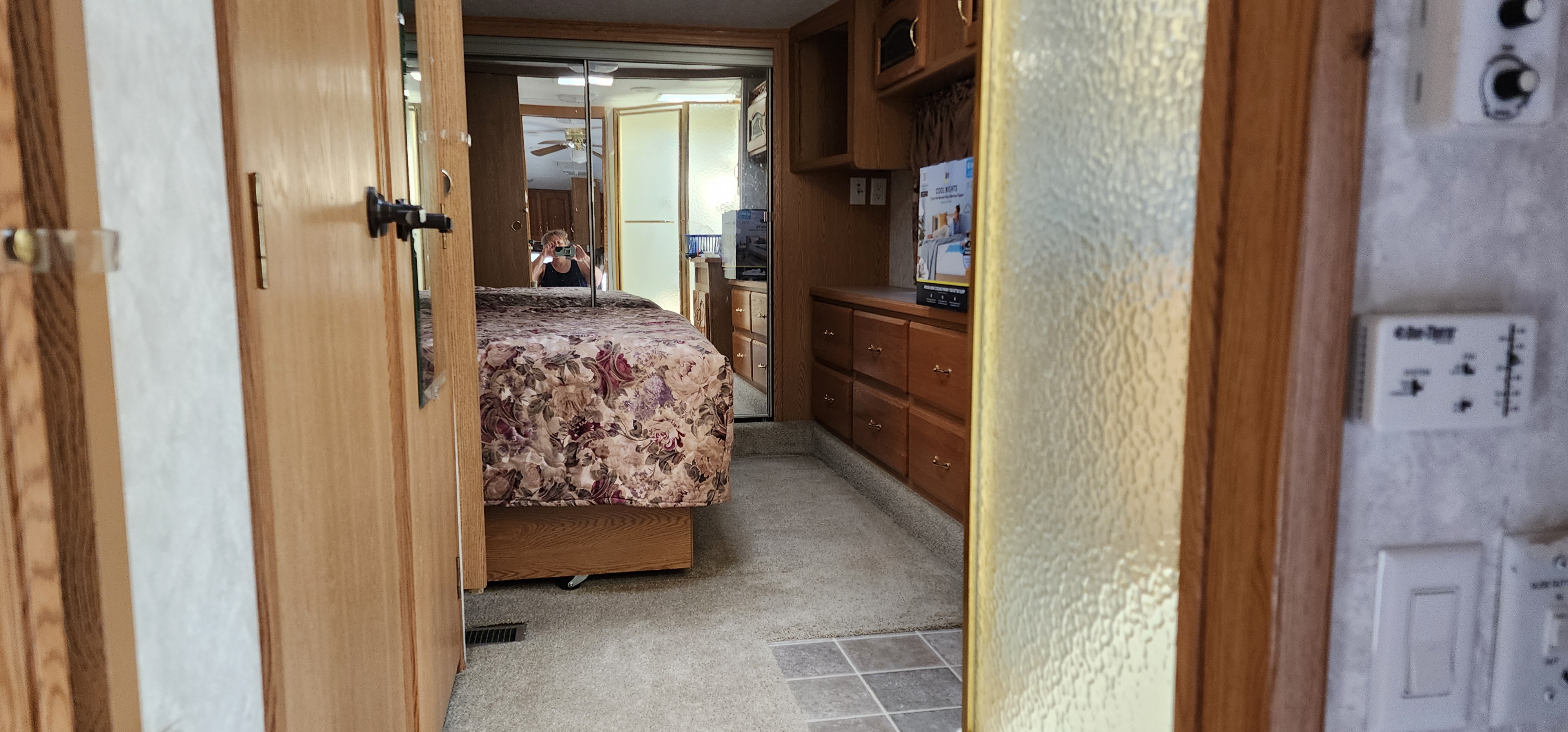 RV rental bedroom: floral bed, wood cabinets, mirrored closet, and TV. A cozy, organized space.. Keystone RV Montana 2004