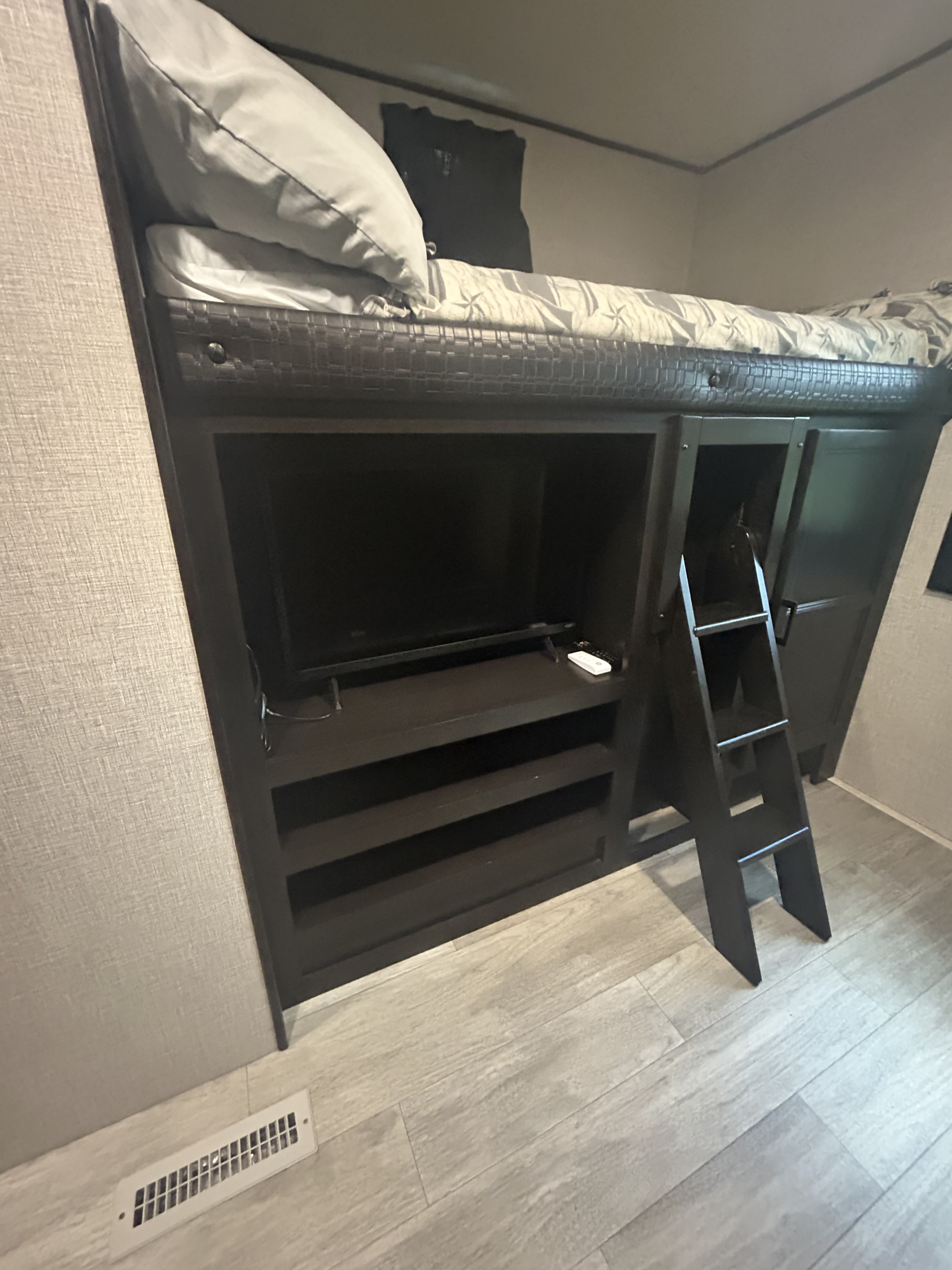 RV rental bunk bed with built-in TV, storage shelves, and access ladder in a compact interior.. Jayco Jay Flight 2022