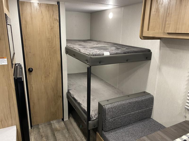 RV rental: Compact interior with two bunk beds, a dining bench, and wood-look door, perfect for family adventures.. Forest River Cherokee Wolf Den EV 2024