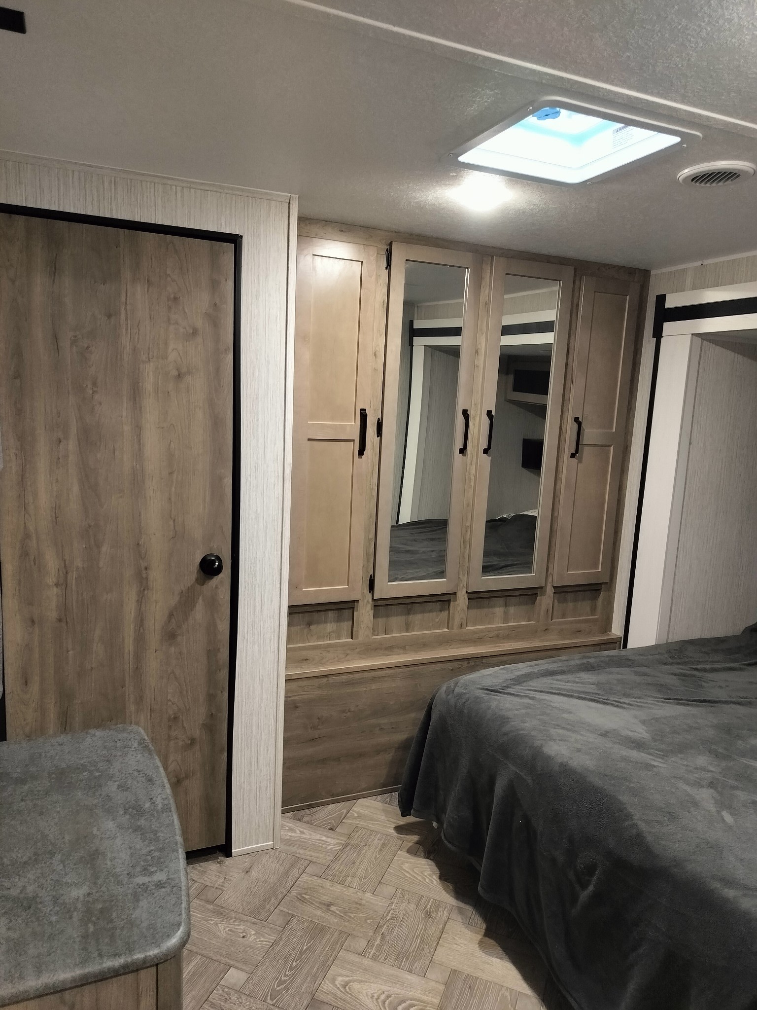 Modern RV rental bedroom with built-in mirrored wardrobe, cozy bed, and bright skylight, perfect for travel.. Forest River Palomino Puma 2022