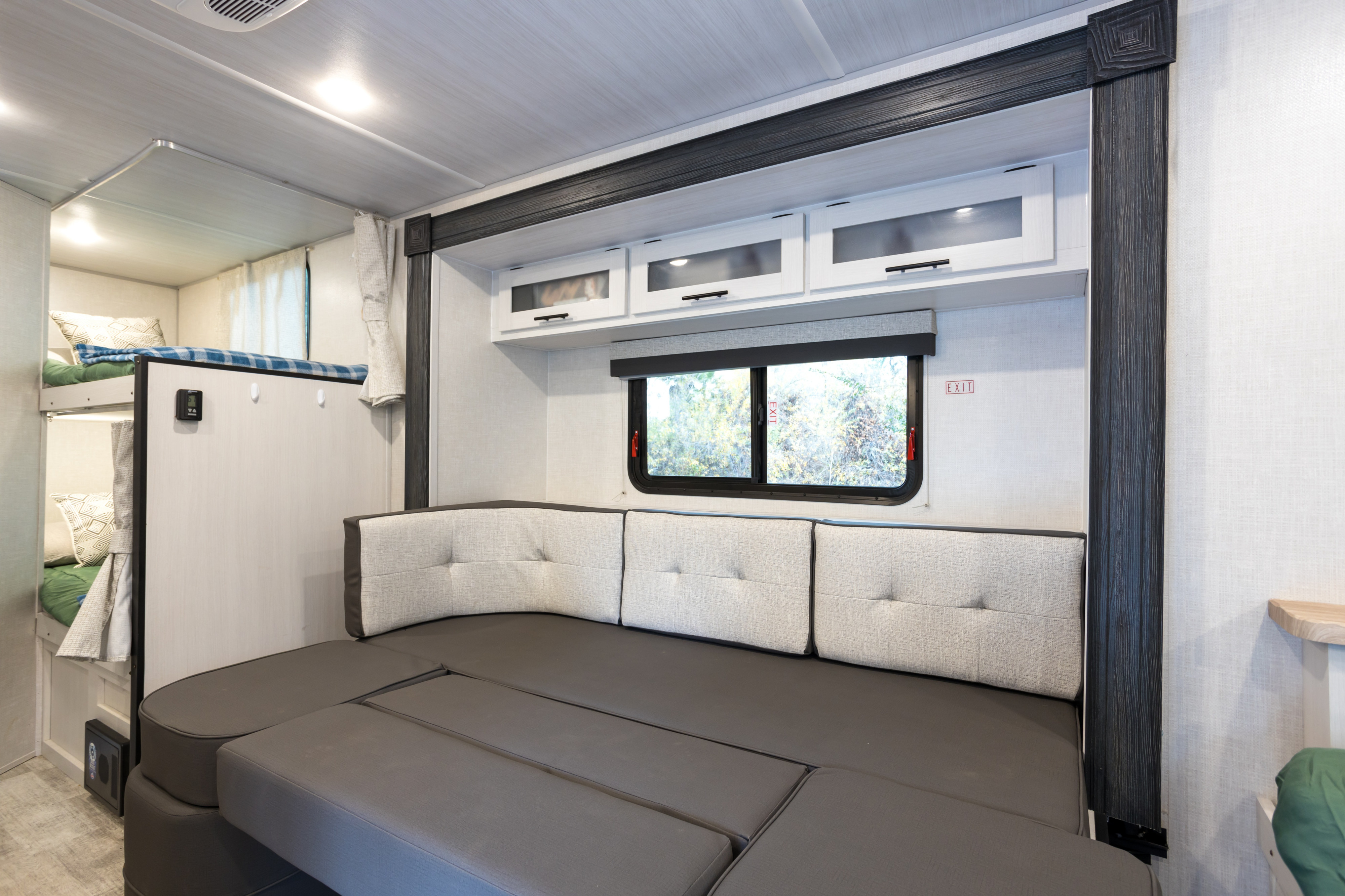Spacious RV rental interior features a convertible bench seat, bunk beds, and overhead storage, ideal for families.. No Boundaries 19 2023