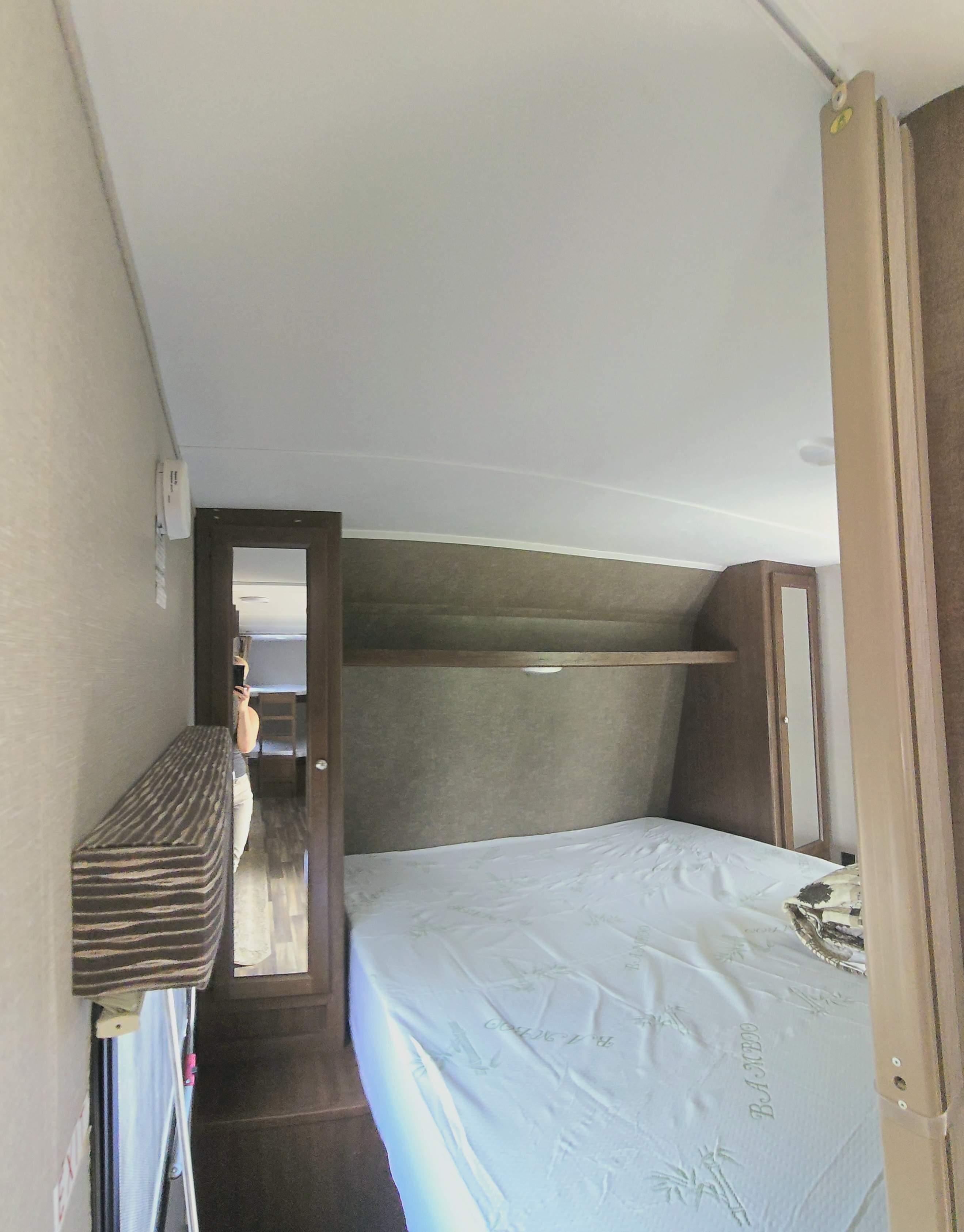 Cozy RV rental bedroom with a bamboo mattress, overhead shelf, and mirrored wardrobe. Ideal for travel comfort.. Keystone RV Hideout 2017
