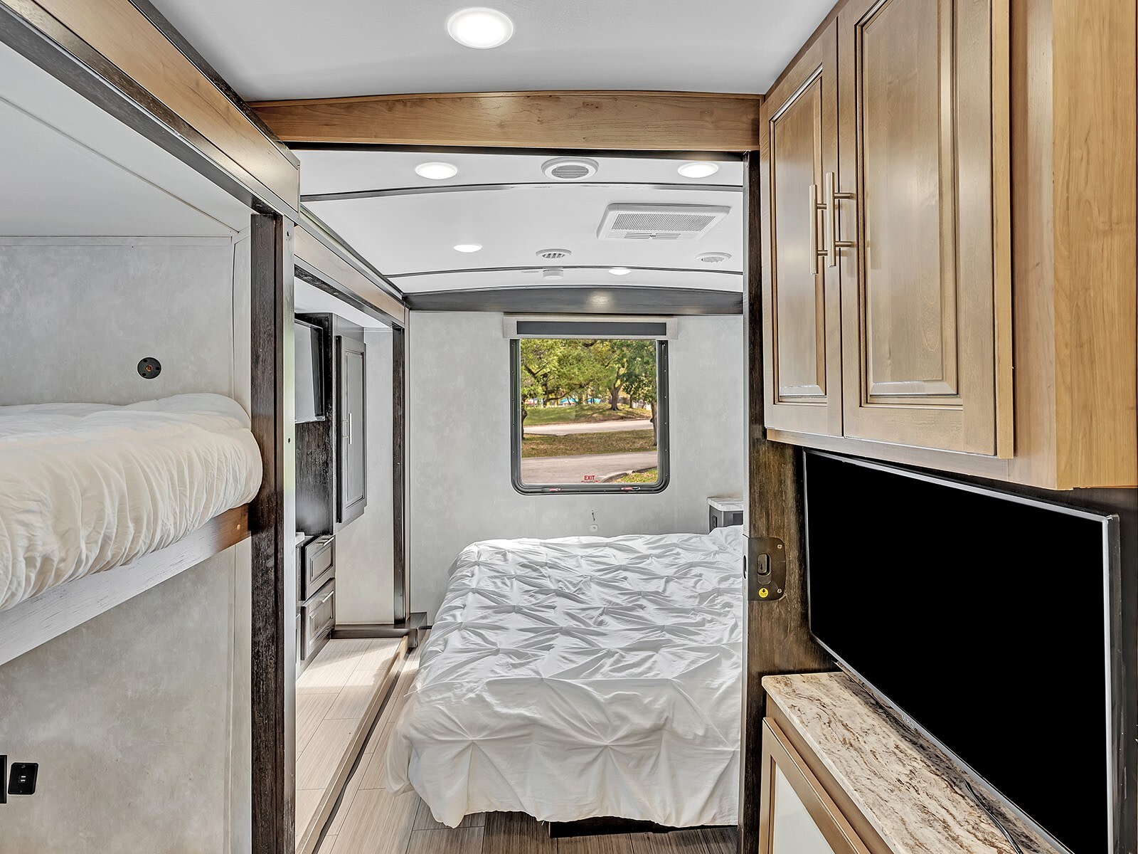 RV rental interior showing a master bed, bunk bed, window view, overhead cabinets, and a TV.. FR3 FR3 Motorhome 2021