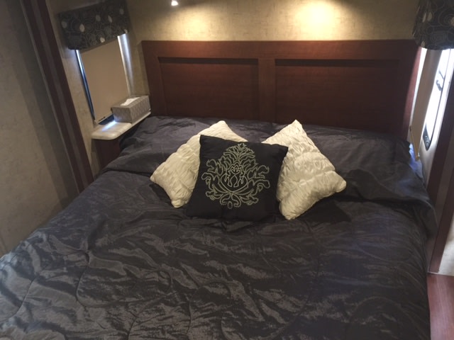 RV rental interior: Comfortable bedroom with dark bedding, wood headboard, and nightstand. A perfect sleeping area.. Forest River Forester 2016
