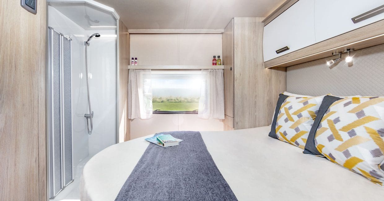 Comfortable RV rental interior: bedroom with bed, scenic window view, and compact shower. Ideal for travel.. Auto-Trail F74 2025