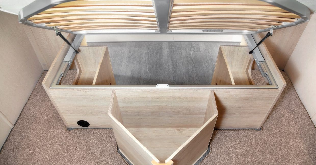 Spacious under-bed storage revealed by a lifted slat base in an RV rental, with built-in compartments.. Auto-Trail F74 2025