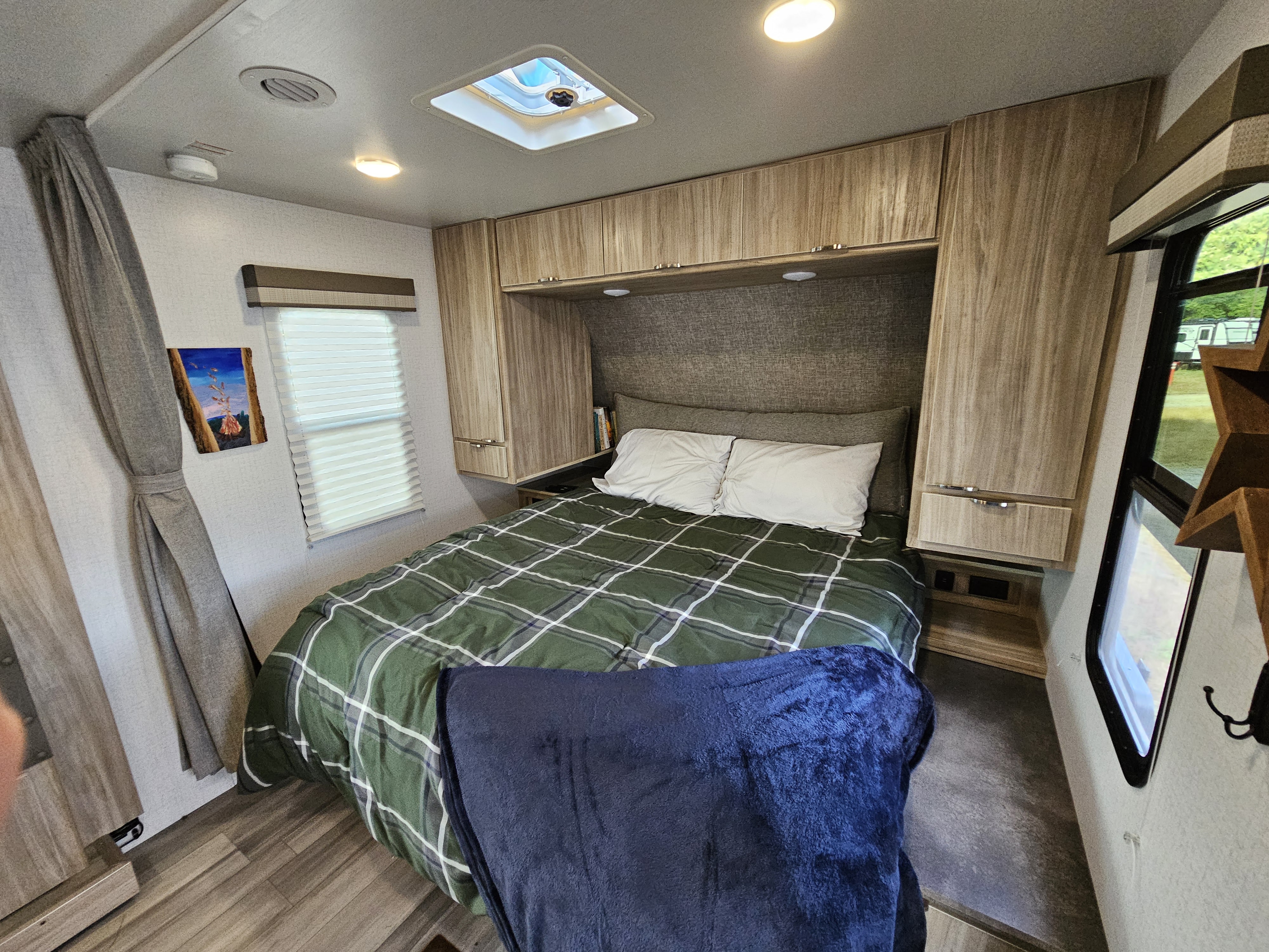 Experience comfortable travel in this RV rental's bedroom, complete with plaid bedding, storage, and natural light.. Winnebago Minnie 2201MB 2022