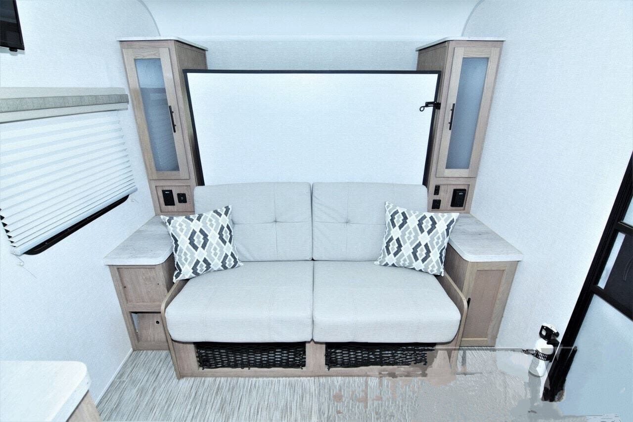 This RV rental's versatile living space features a comfortable sofa, a hidden bed mechanism, and clever storage solutions.. No Boundaries 19 2021