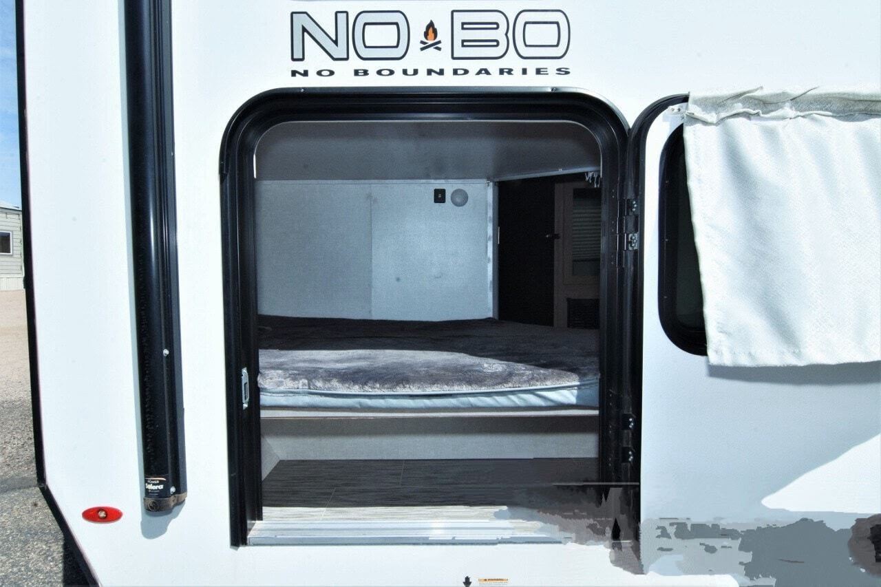 RV rental: Interior view of a NO BO camper's sleeping area through the open rear door. Features a bed, floor, and curtain.. No Boundaries 19 2021