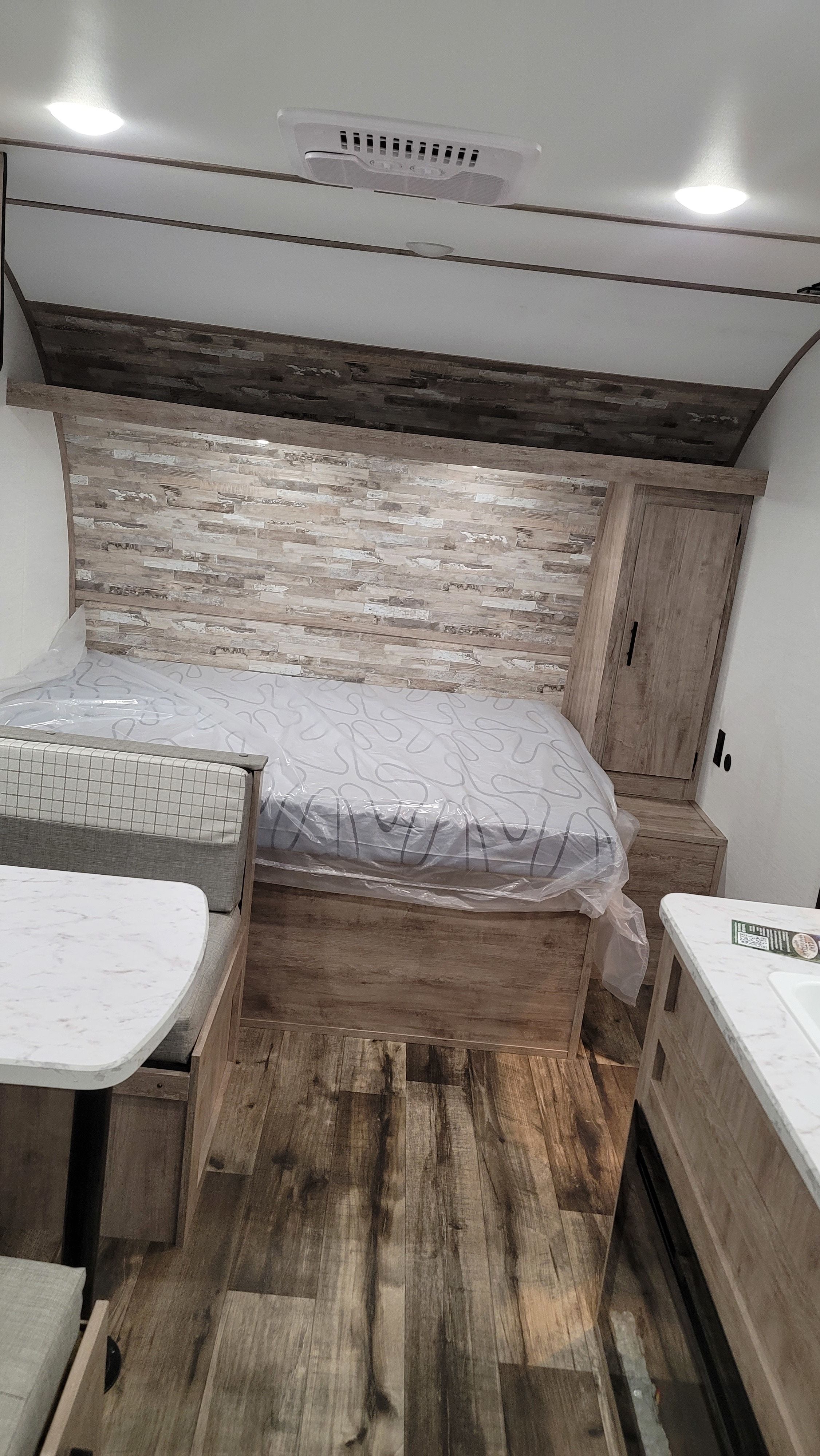 Modern RV rental interior with a bed, built-in dining booth, and compact kitchenette for comfortable travel.. Gulf Stream Ameri-Lite 2024