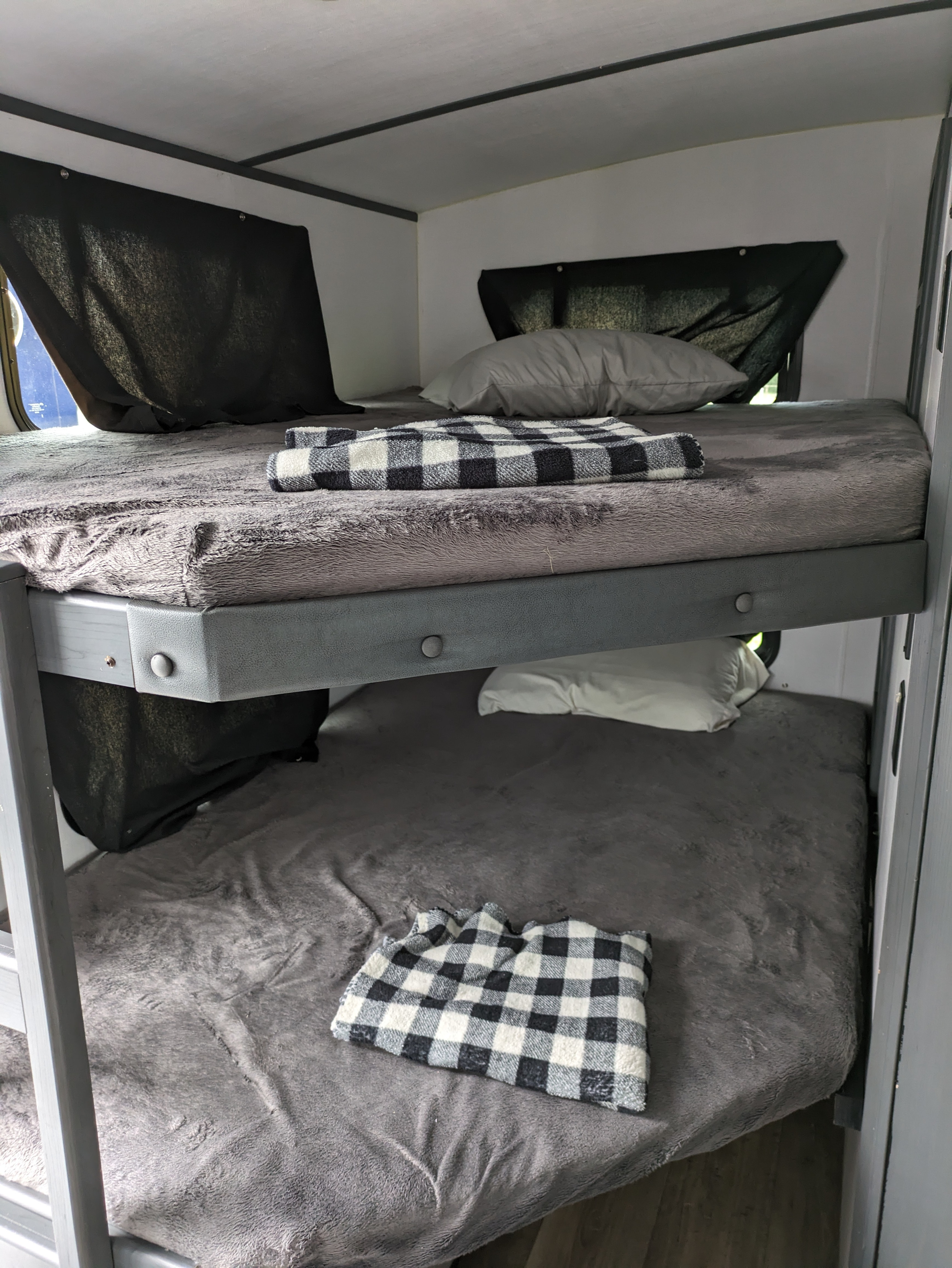 Cozy bunk beds inside an RV rental, featuring soft grey bedding and plaid blankets, ready for adventure.. Keystone RV Bullet Premier Ultra Lite 2022