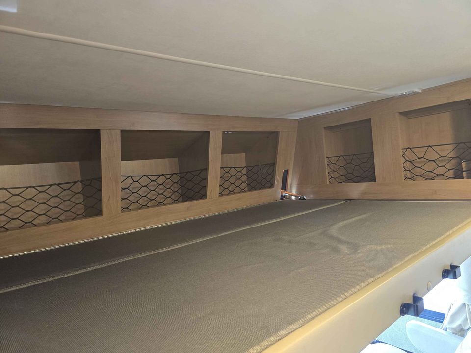 RV rental interior: A sleeping area featuring overhead storage cubbies with secure mesh netting.. Thor A.C.E. 2018