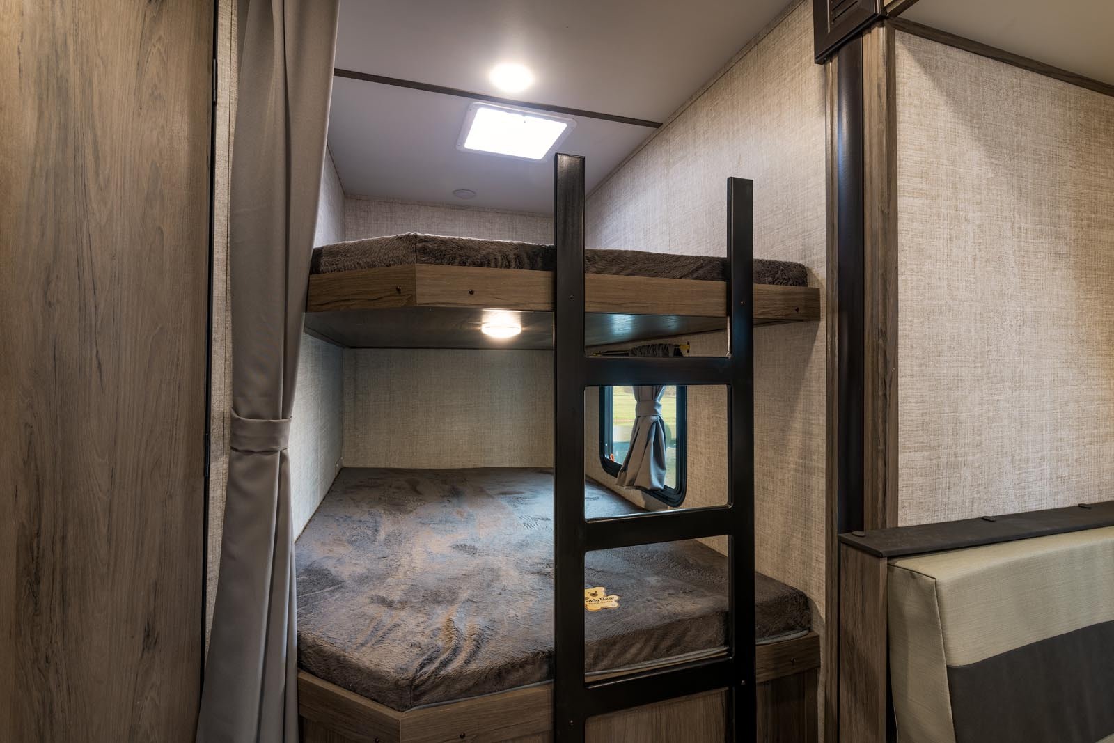 RV rental: Cozy bunk beds in a camper, featuring a ladder, window, and overhead skylight for comfortable sleeping.. Gulf Stream Ameri-Lite 2024