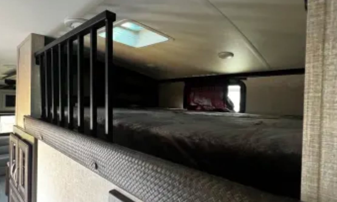 Cozy RV rental bunk bed with skylight and safety railing, ready for adventure.. Jayco North Point 2023
