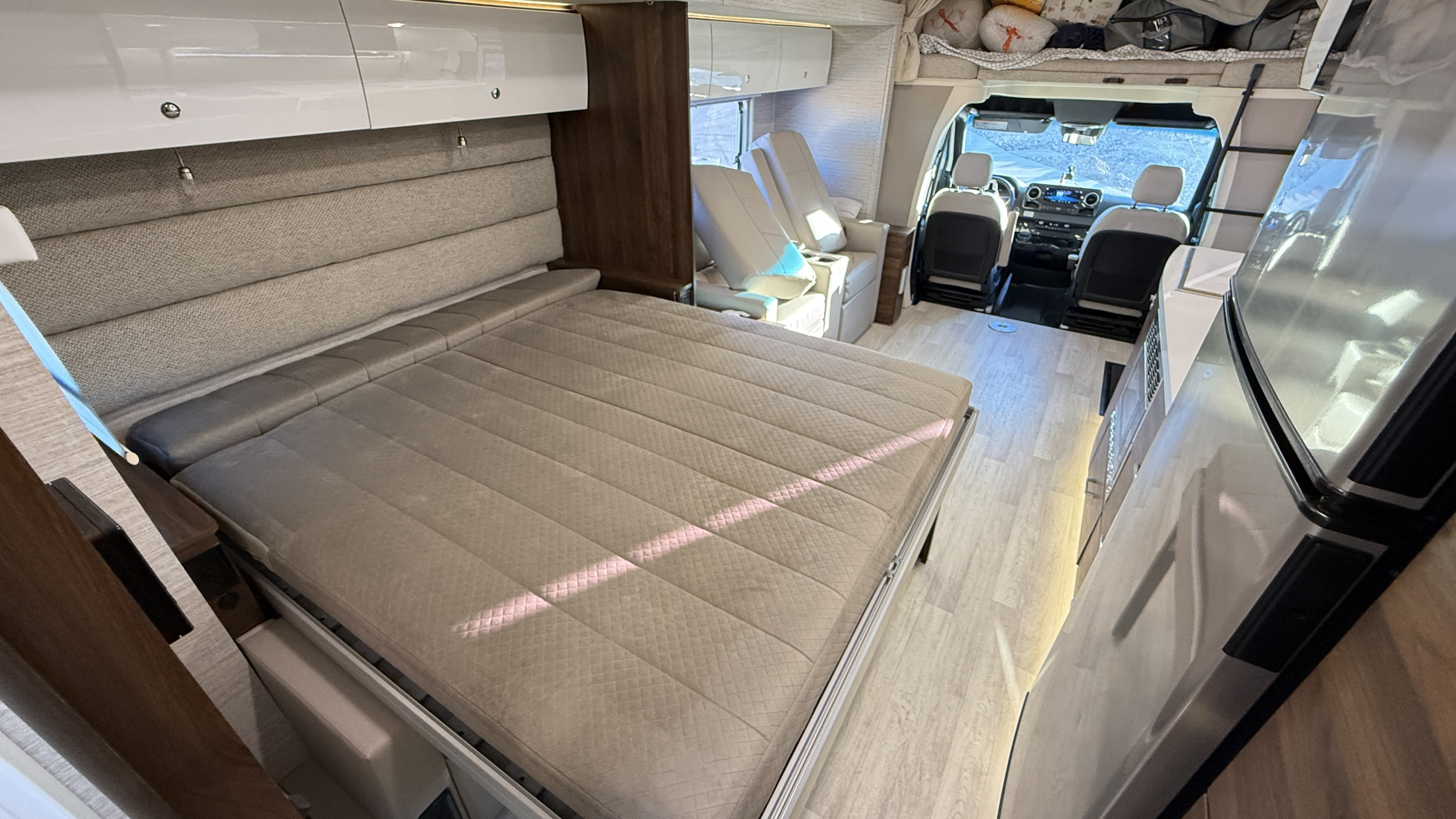 Spacious rv rental interior: large bed, kitchen, and driver's cabin with light wood floors. Modern design.. Winnebago View 24D 2022