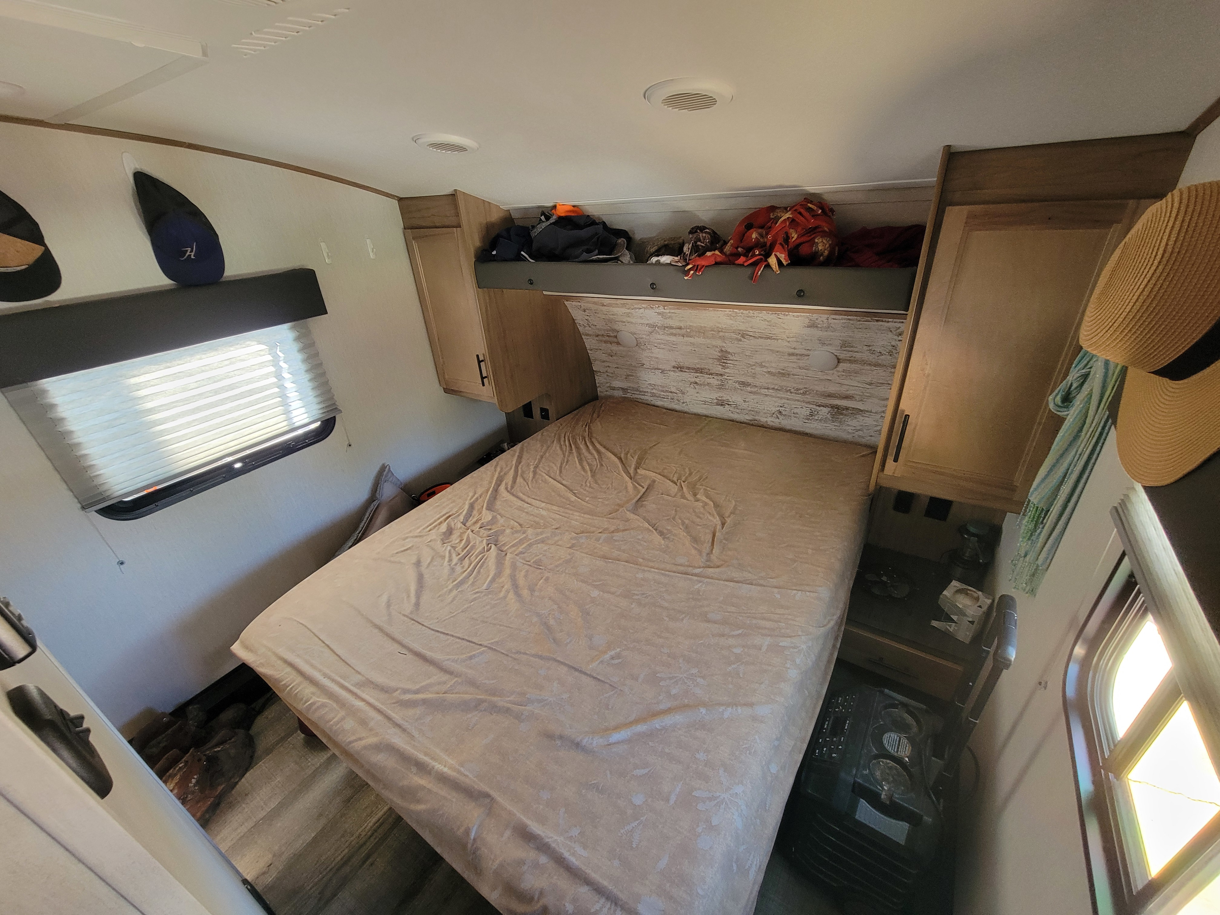 Cozy RV rental bedroom with a large bed, overhead storage, compact design, and natural light from windows.. Forest River Cherokee Arctic Wolf 2023