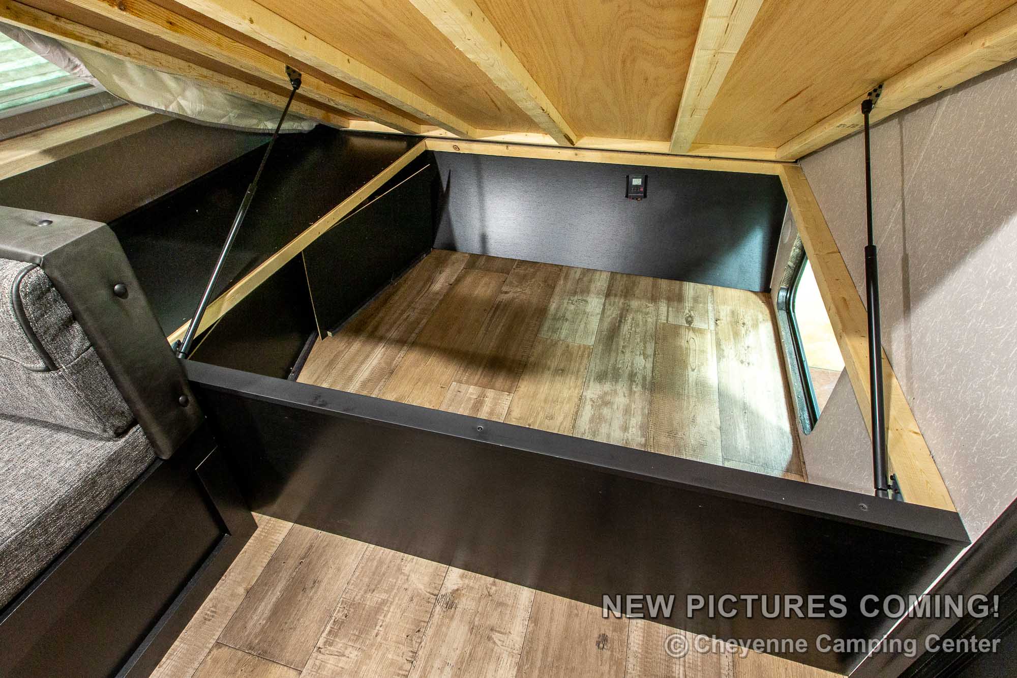 Discover practical under-bed storage in this RV rental, featuring durable wood-look flooring and gas strut support. Ideal for camper trips.. Forest River Cherokee Wolf Pup Black Label 2022