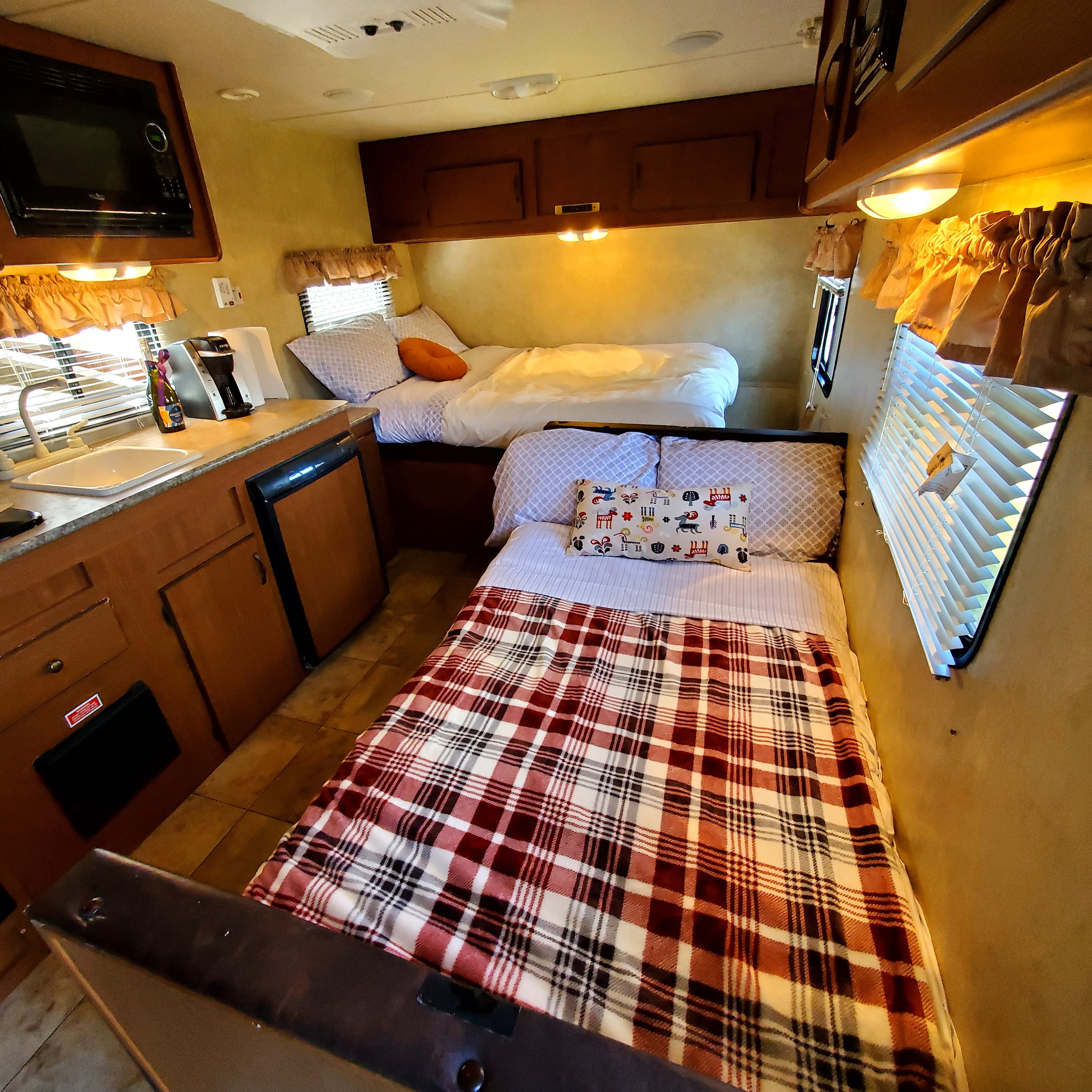Cozy RV rental interior featuring a compact kitchen, two beds, and warm lighting, perfect for travel adventures.. Forest River Stealth Evo T185RB 2014