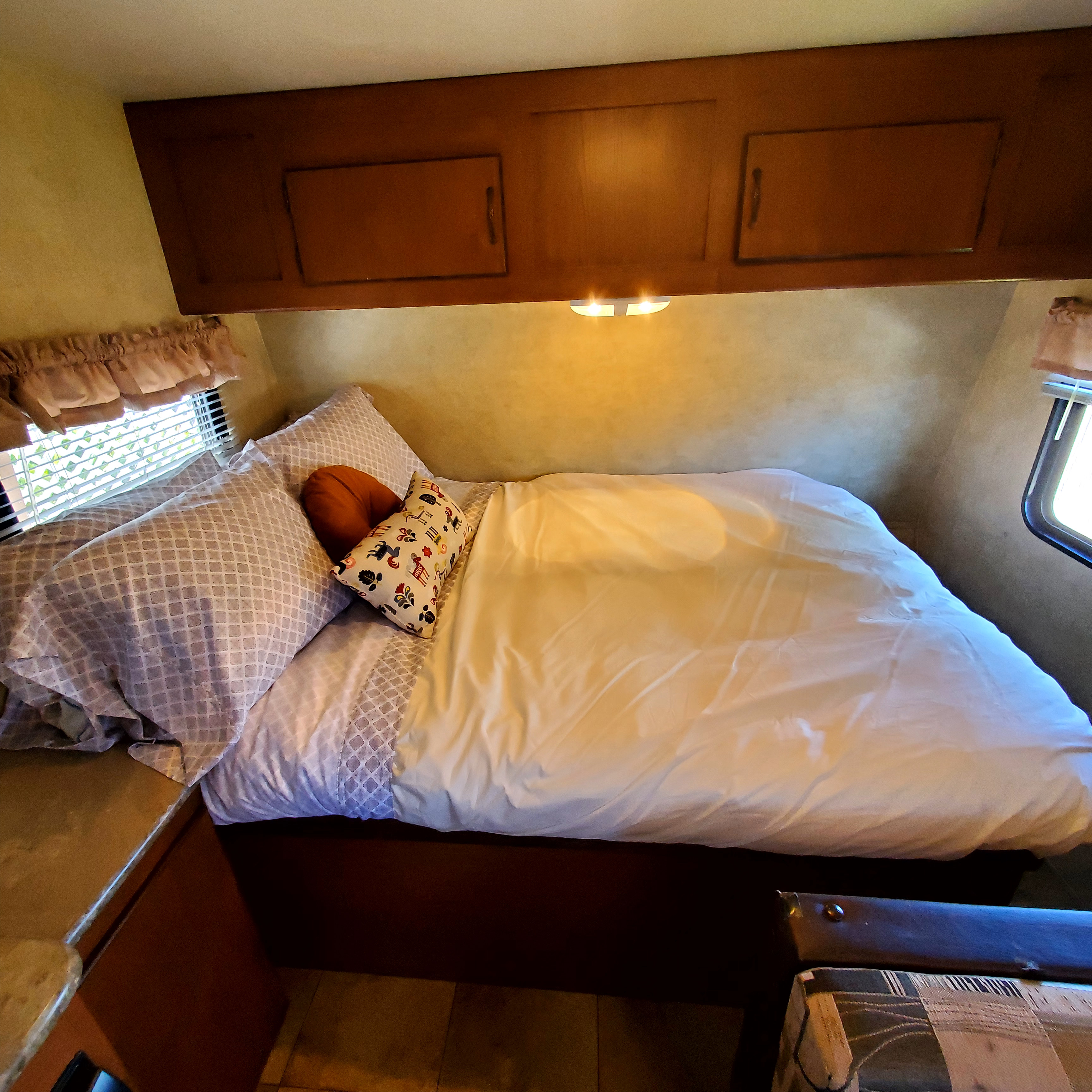 Compact RV rental bedroom with a cozy bed, patterned pillows, overhead storage, and window, ready for your next adventure.. Forest River Stealth Evo T185RB 2014