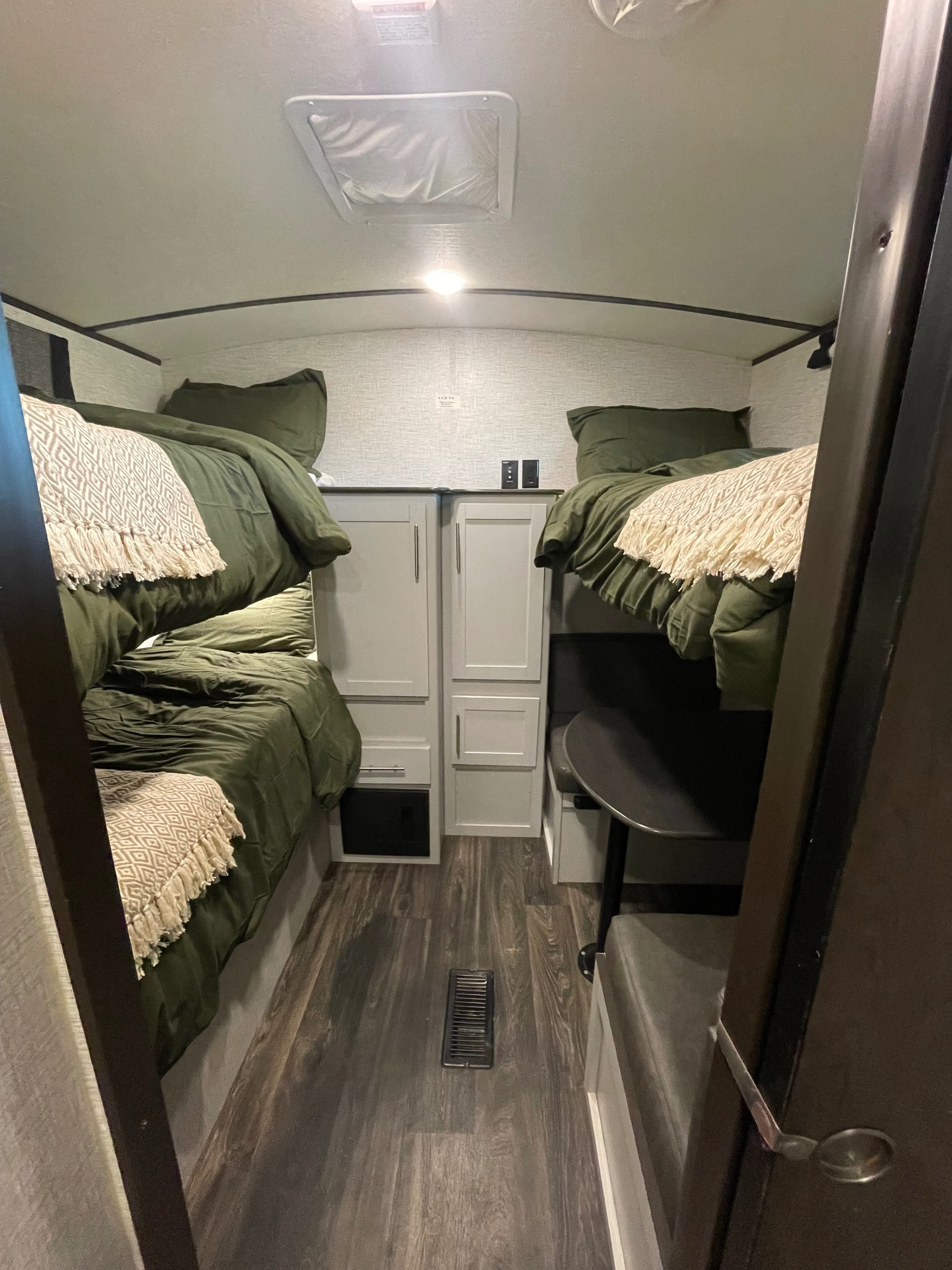 This RV rental interior features comfortable bunk beds with green bedding, a dinette, and storage cabinets.. Keystone RV Bullet Ultra Lite 2021