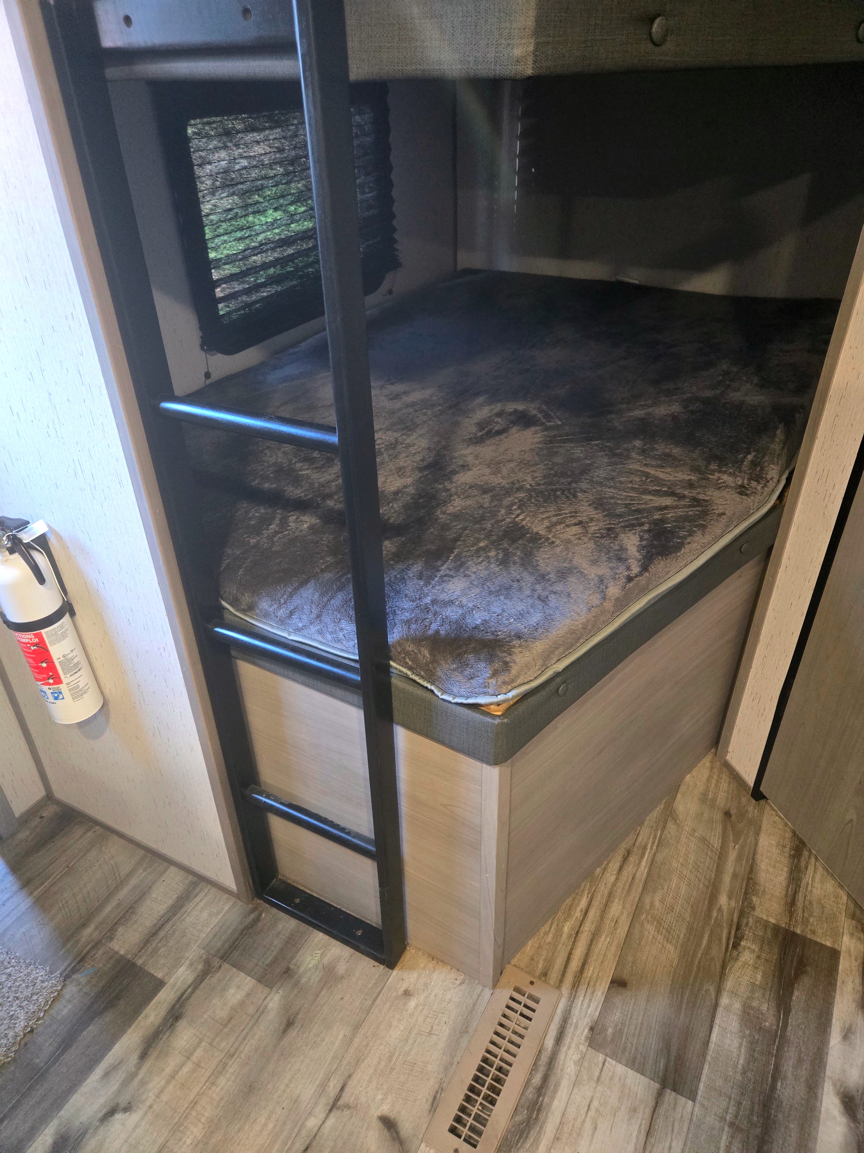 Explore this cozy RV rental's bunk bed area, featuring a ladder, window with blinds, fire extinguisher, and wood-look flooring.. Dutchmen Coleman Lantern 2022