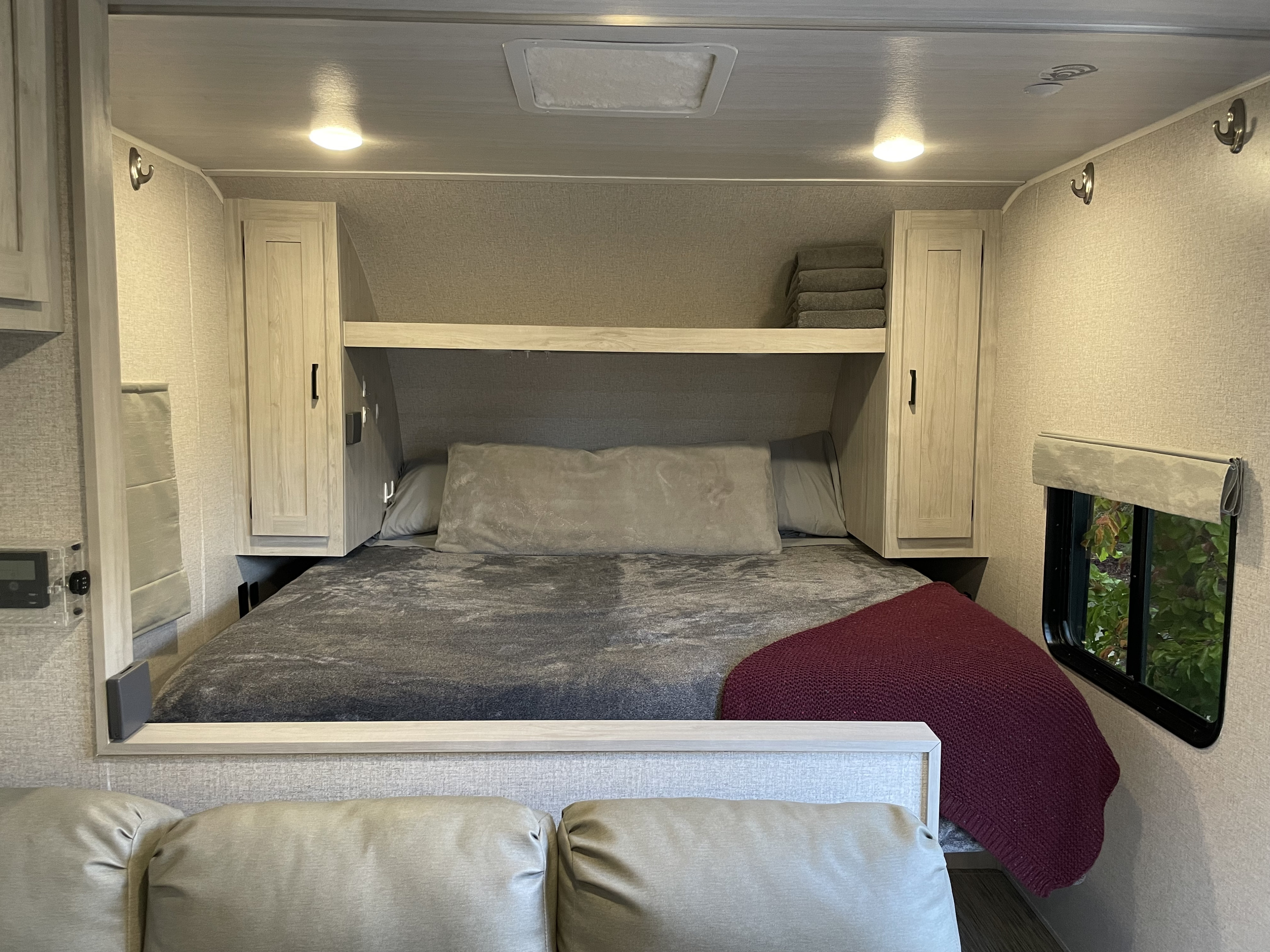 Comfortable RV rental bedroom with modern design, overhead storage, and window views.. East to West Silver Lake LE 2023