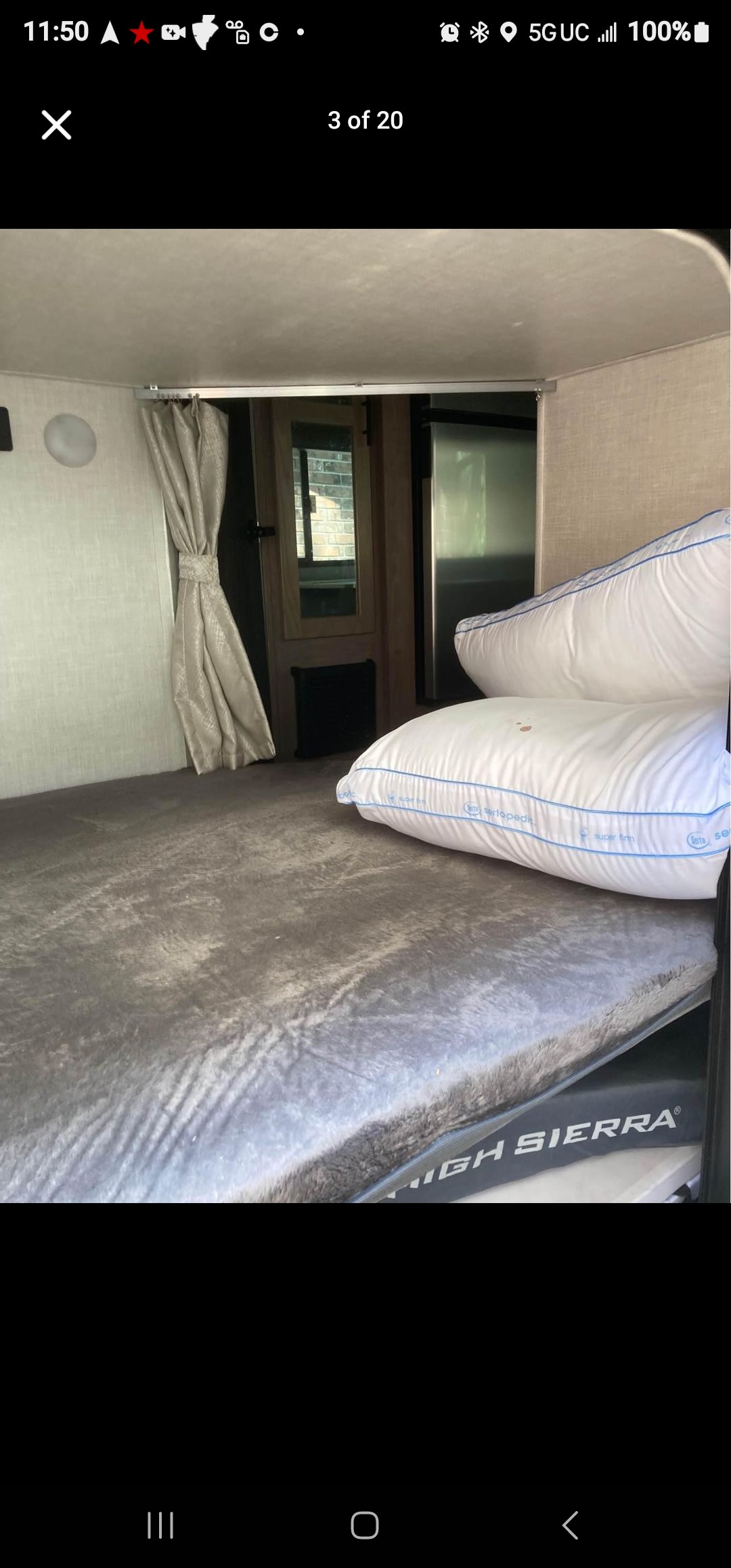 Inside an RV rental: a cozy bunk bed area with a grey blanket, white pillows, a tied-back curtain, and High Sierra bedding.. No Boundaries 19 2021