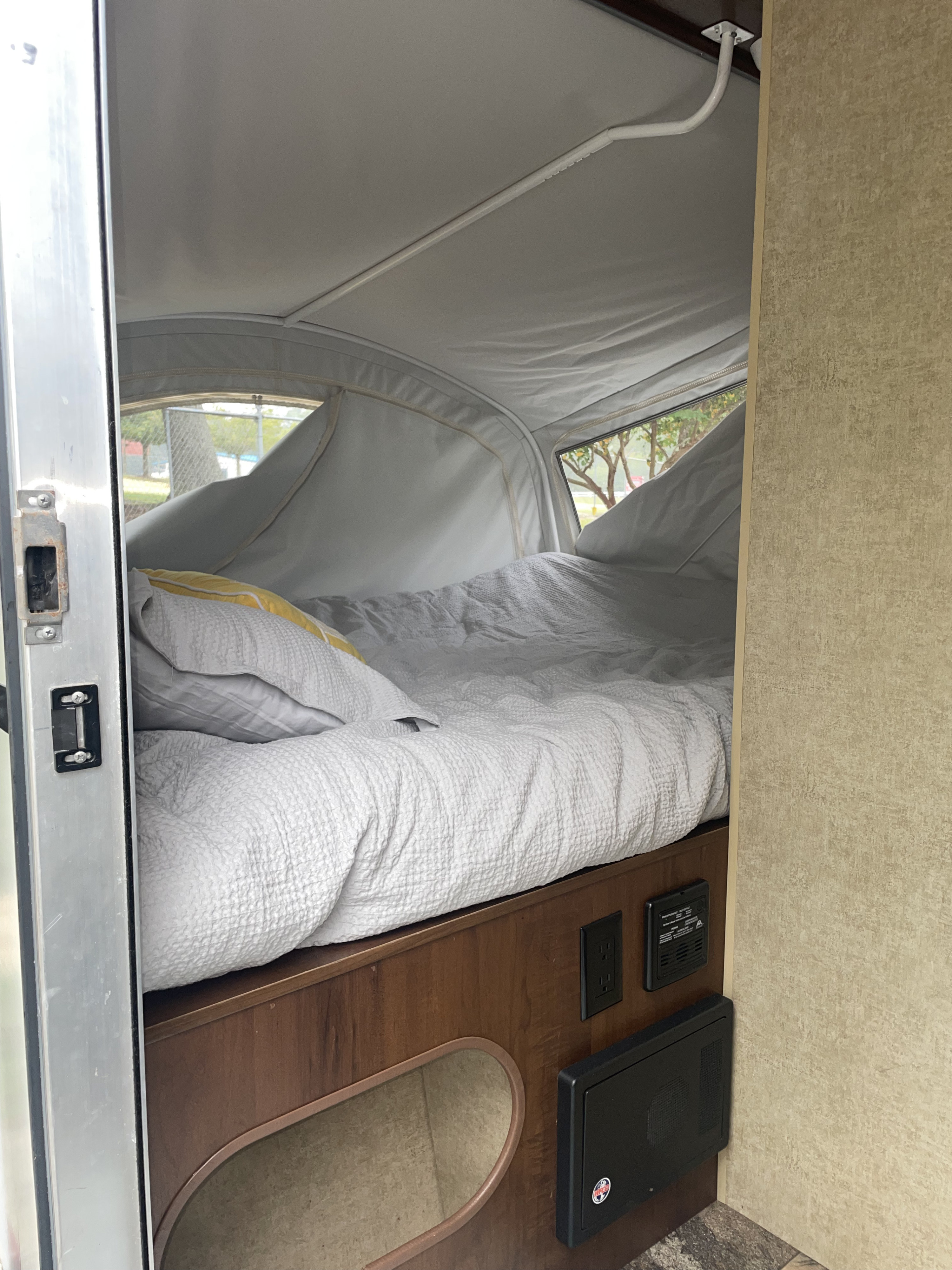 Cozy RV rental interior with a made-up bed, canvas walls, and essential electrical outlets, ideal for camping.. Jayco Jay Feather Ultra Lite SLX 2014