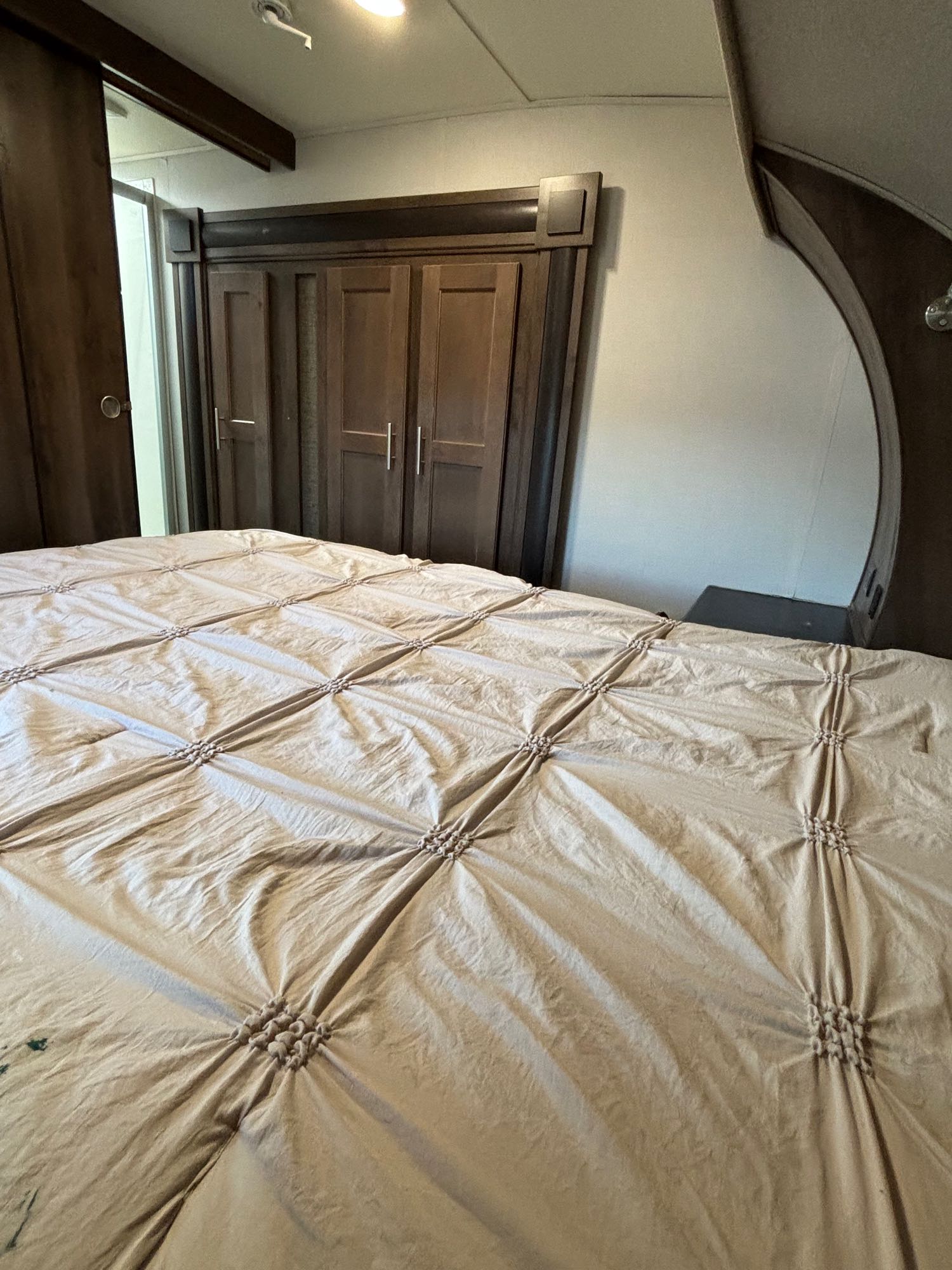 Cozy RV rental bedroom featuring a large bed with a patterned comforter and built-in wooden wardrobe.. Forest River Wildcat Maxx 2017