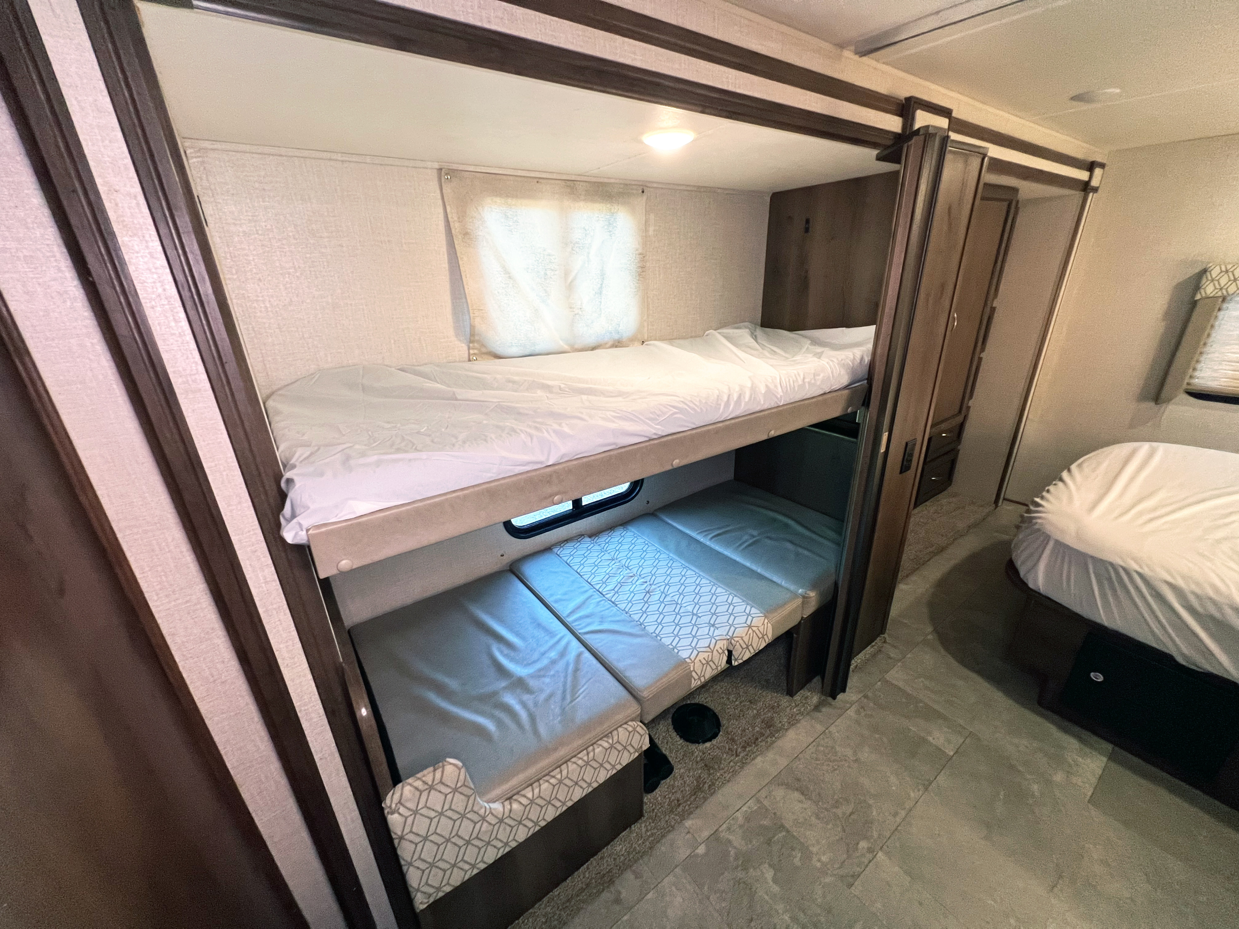 This RV rental interior offers cozy bunk beds, including a lower convertible sleeping area, plus a master bed for family trips.. Forest River Freelander 2020