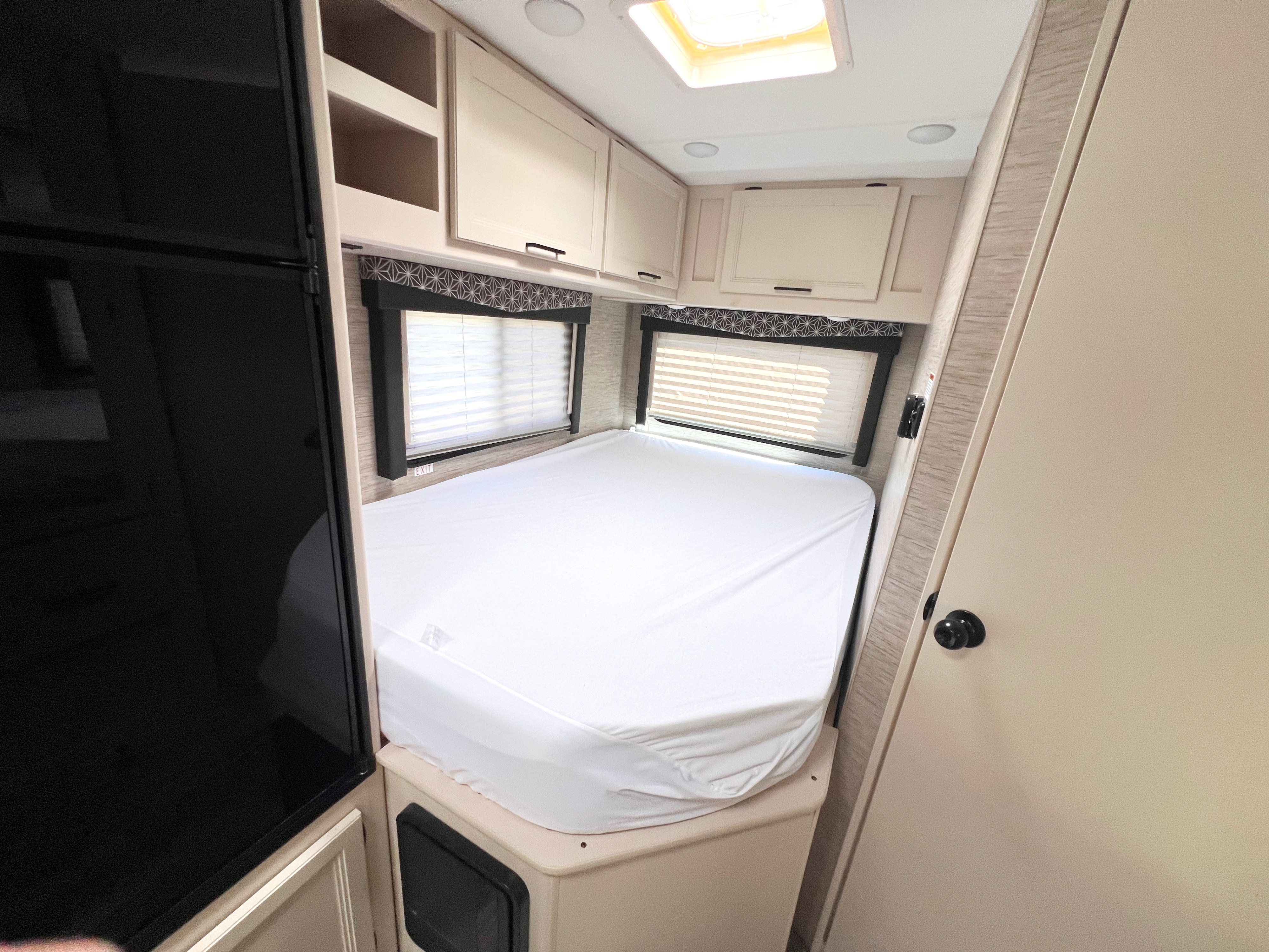 RV rental: Bright bedroom with white bed, windows, and overhead storage cabinets. Ready for your cozy mobile adventure.. Thor Freedom Elite 2022