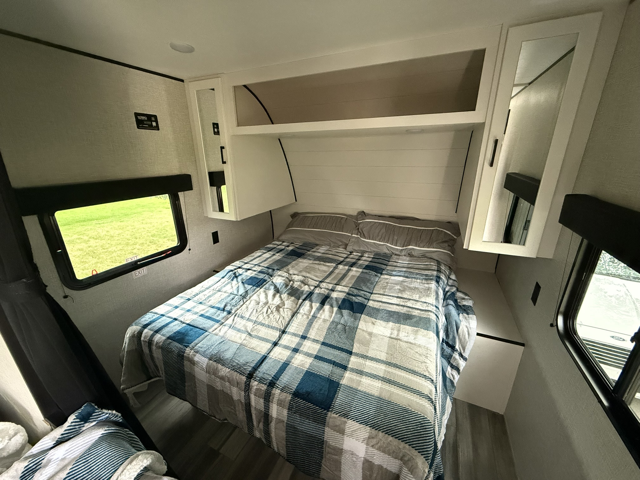Cozy RV rental bedroom with a plaid bed, overhead storage, and side windows.. Jayco Jayflight SLX 260BH 2025
