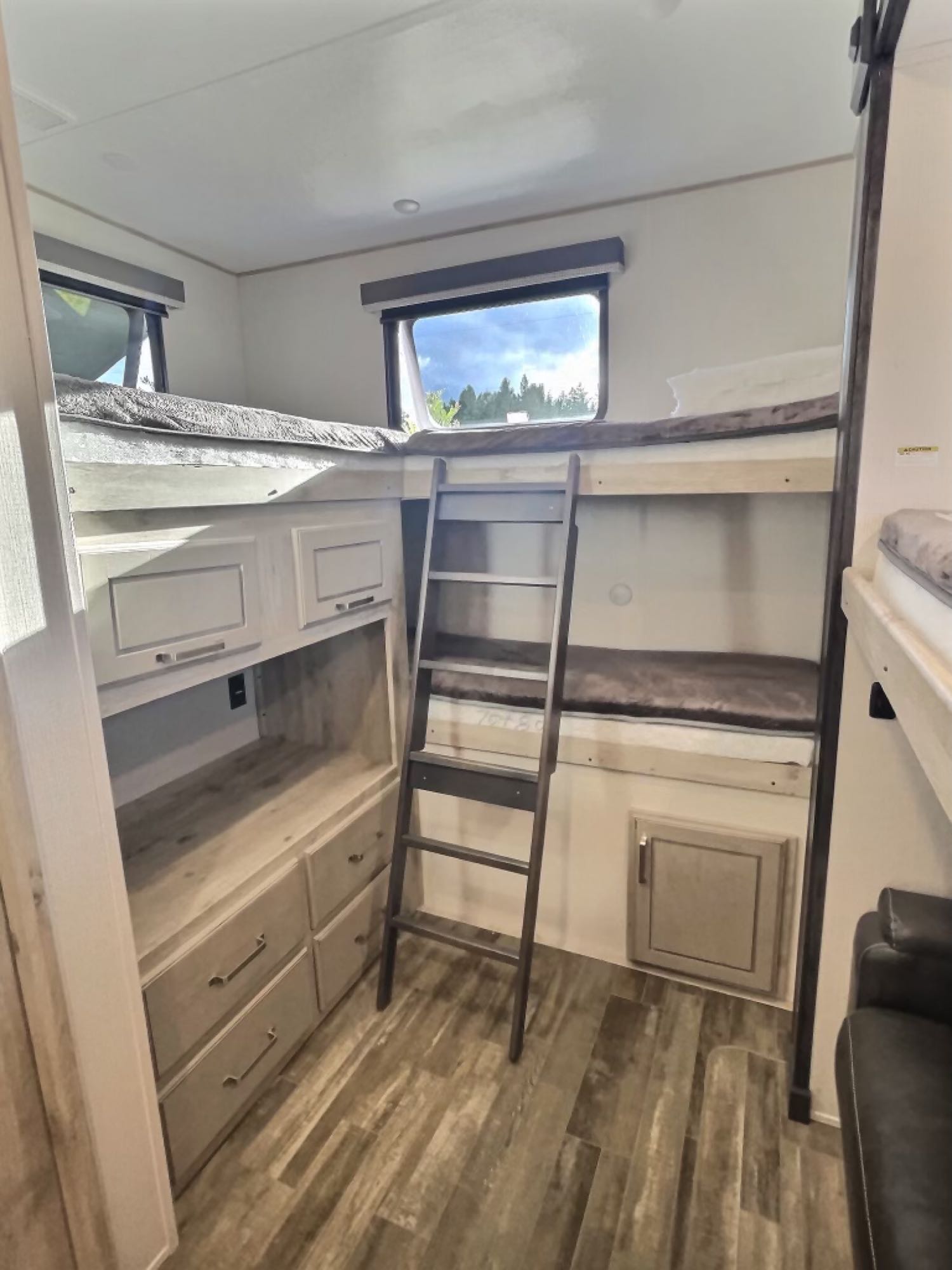 RV rental interior featuring a bunkhouse with two beds, ladder, storage, and windows. Ideal for family trips.. Keystone RV Avalanche 2022