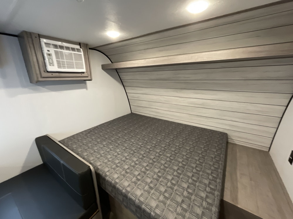 Compact RV rental interior with a bed, bench, and AC unit. Perfect for efficient, tiny living.. Coleman Lantern 17BH 2025
