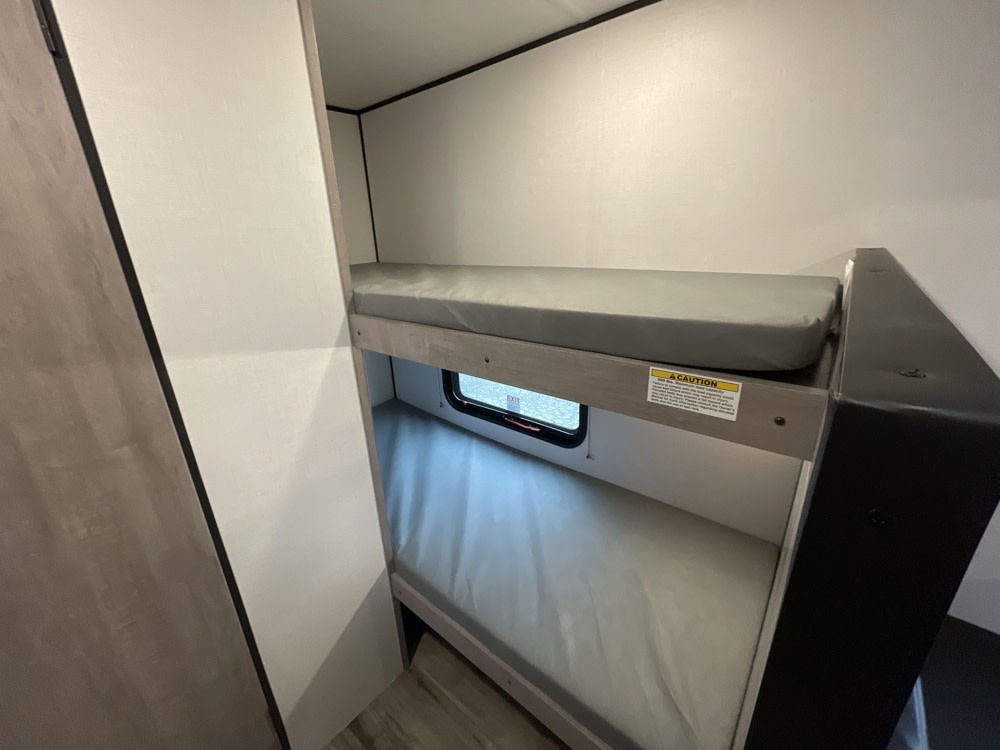 Inside an RV rental: a cozy sleeping area featuring bunk beds. The lower bunk includes a small window.. Coleman Lantern 17BH 2025