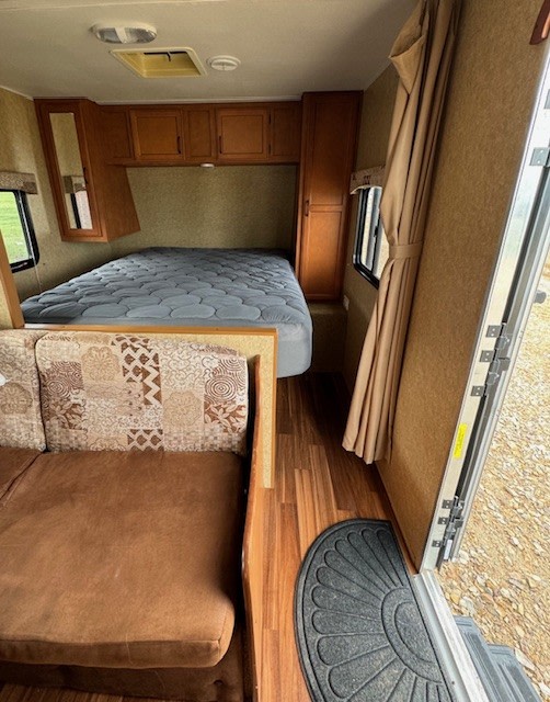 RV rental interior: view of comfortable bed, patterned sofa, wood cabinets, and open entry, ideal for travel.. Gulf Stream Kingsport SE 2014