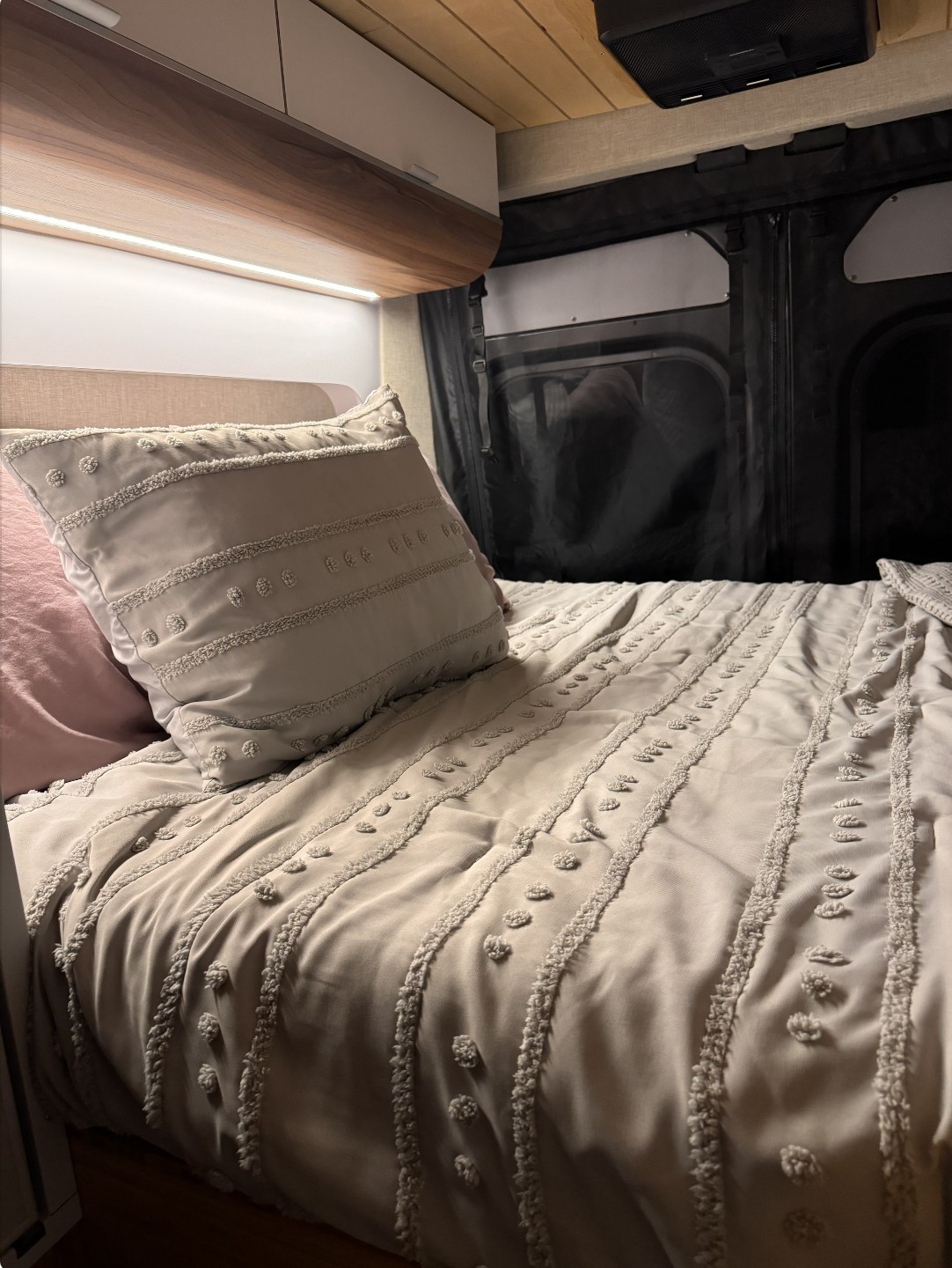 Explore a cozy RV rental interior: soft grey bed, accent lighting, and modern cabinets for comfortable travel.. Noovo Pop 2024