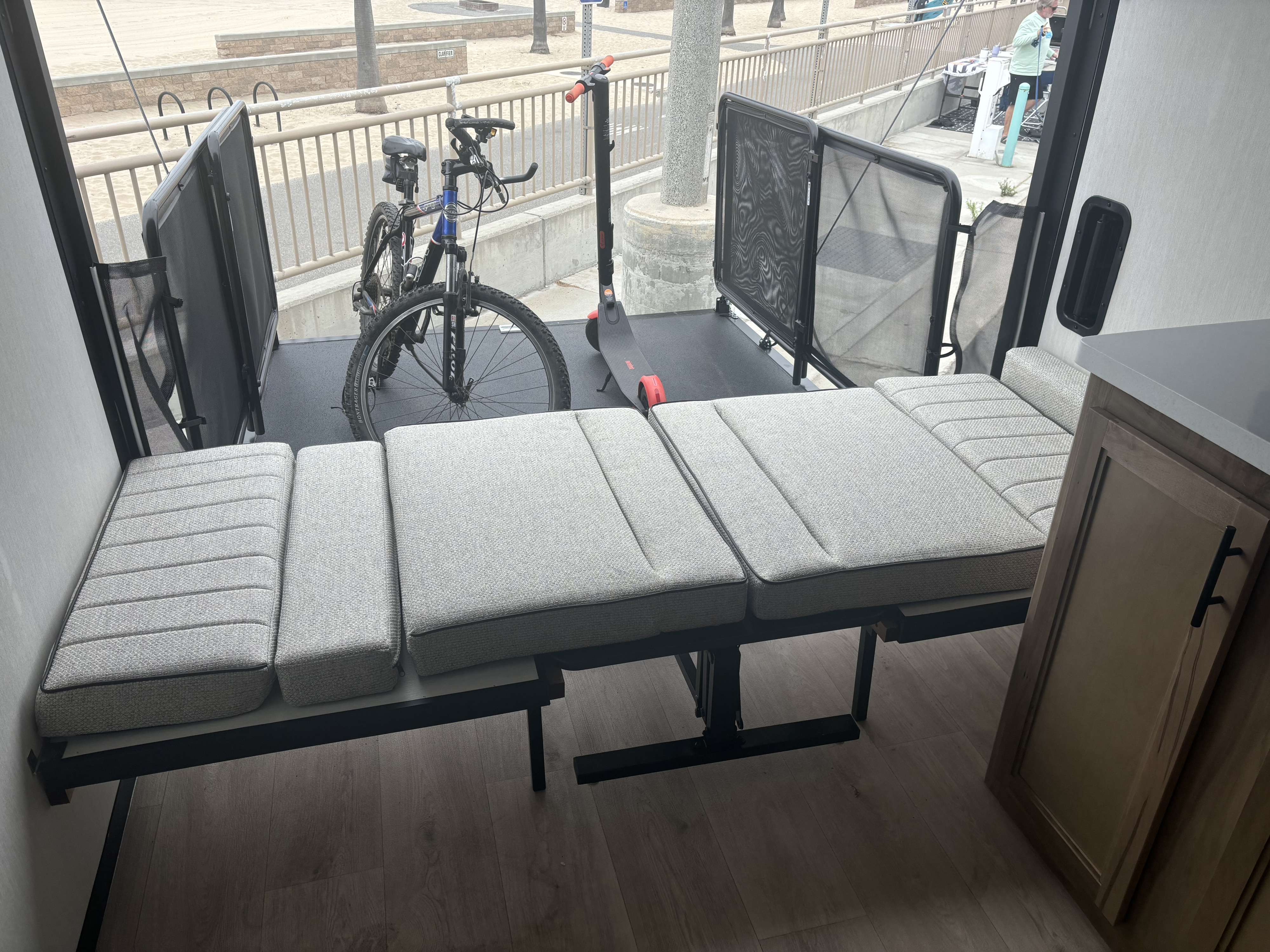 RV rental toy hauler with versatile interior: sofa converts to bed, bikes & scooter on the outdoor patio overlooking the beach.. Forest River Wolf Pup 2025