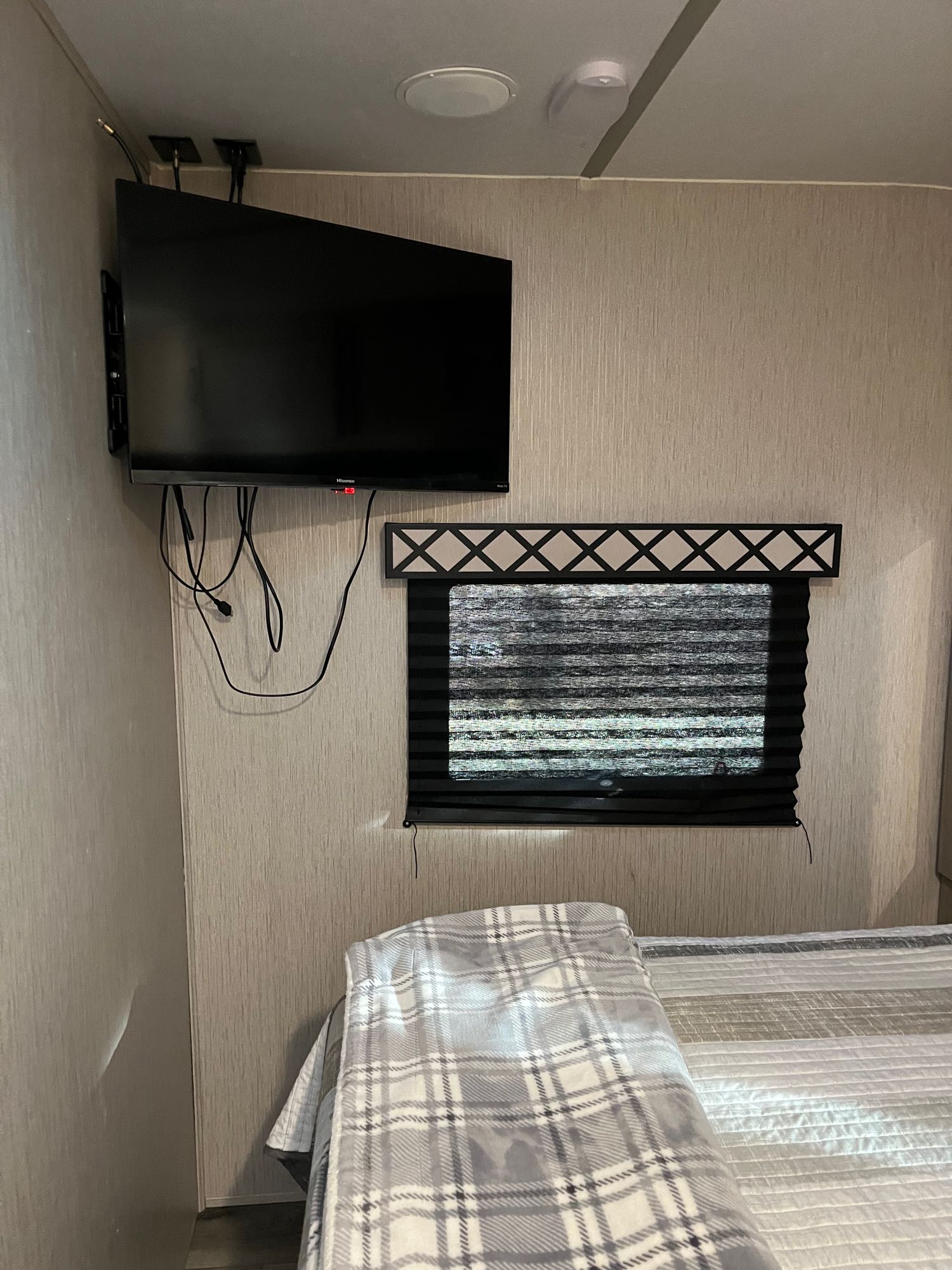 Compact RV rental bedroom with wall-mounted TV, window, and bed, perfect for a cozy stay.. Coachmen Freedom Express Ultra Light 2020