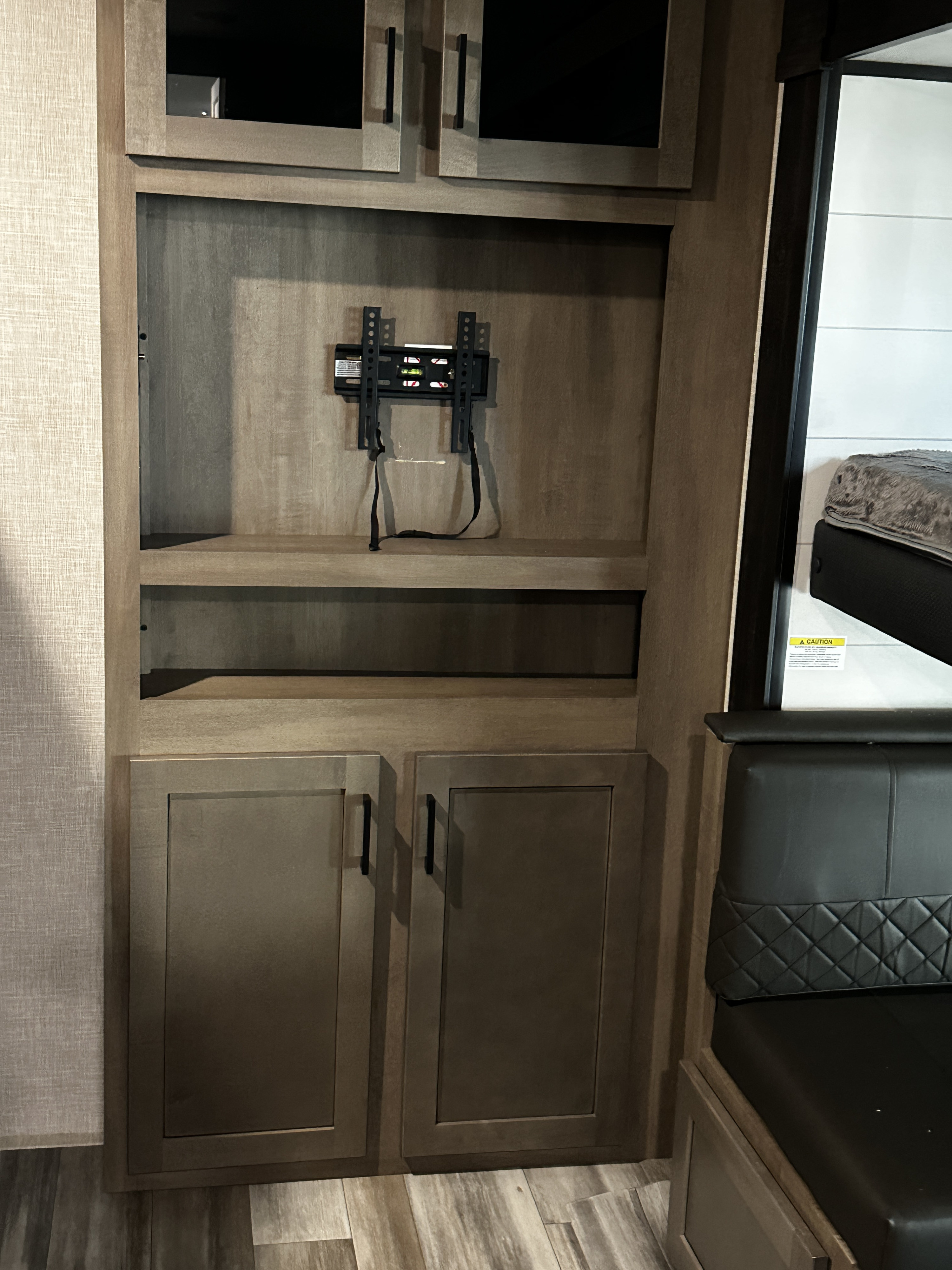 RV rental interior features neutral-toned cabinetry, TV mount, open shelving, and a modern dinette area with an overhead bed.. Jayco Jay Flight 2024